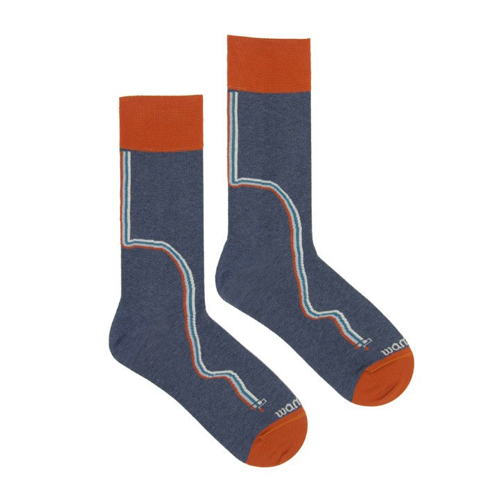 Ein Paar blaue Socken mit orangefarbenen Bündchen, Fersen und Zehen. Jede Socke ist mit einer geschwungenen weißen und orangefarbenen Linie versehen, die über die gesamte Länge der Socke verläuft.