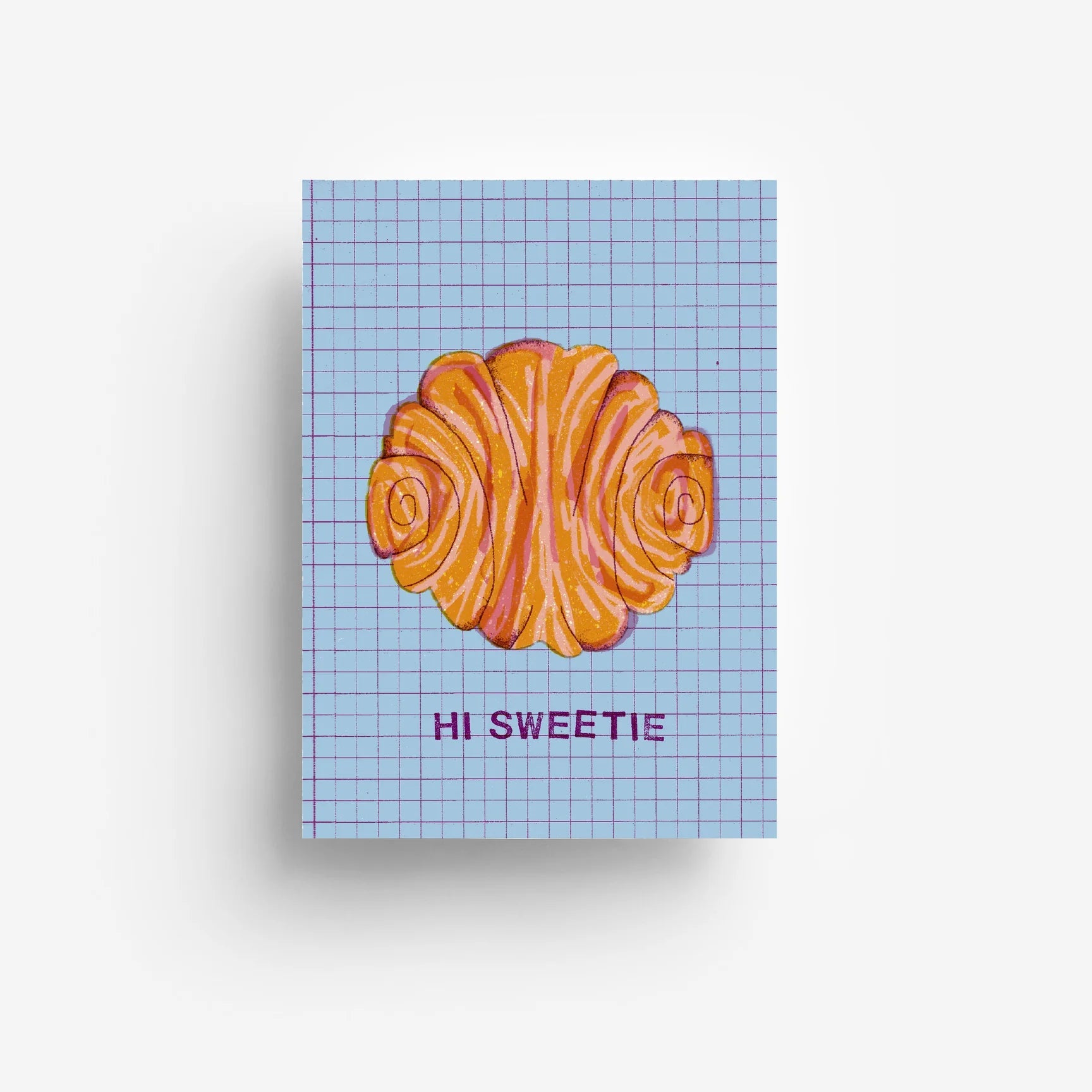 Eine Grußkarte mit einem gemalten Croissant auf einem blauen Gitterhintergrund und dem Text "HI SWEETIE" in lila Buchstaben darunter.