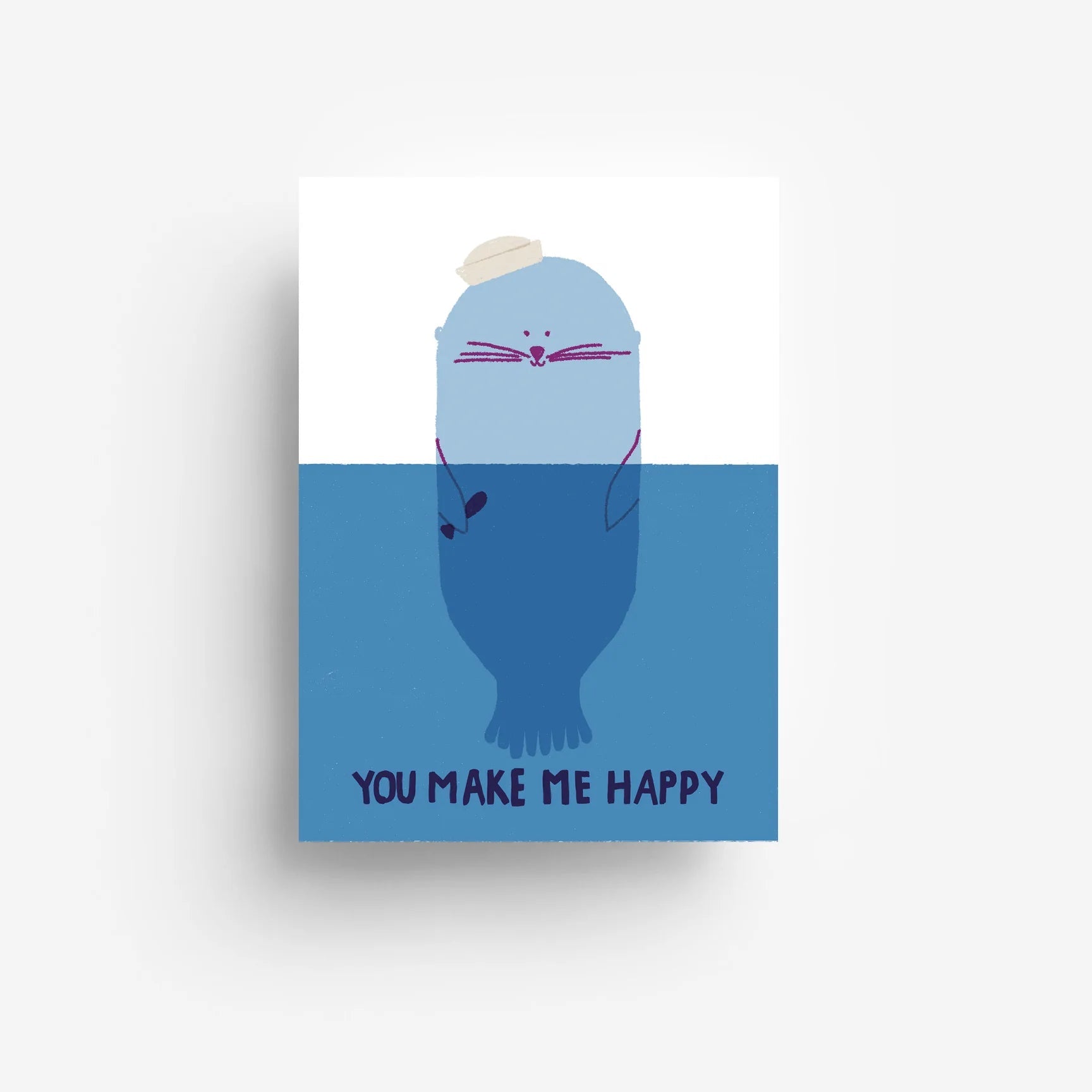 Eine niedliche blaue Robbe mit einem kleinen weißen Hut schwimmt im Wasser und lächelt mit geschlossenen Augen. Darunter steht in dunkelblauen Lettern YOU MAKE ME HAPPY. Der Hintergrund ist weiß und blau.