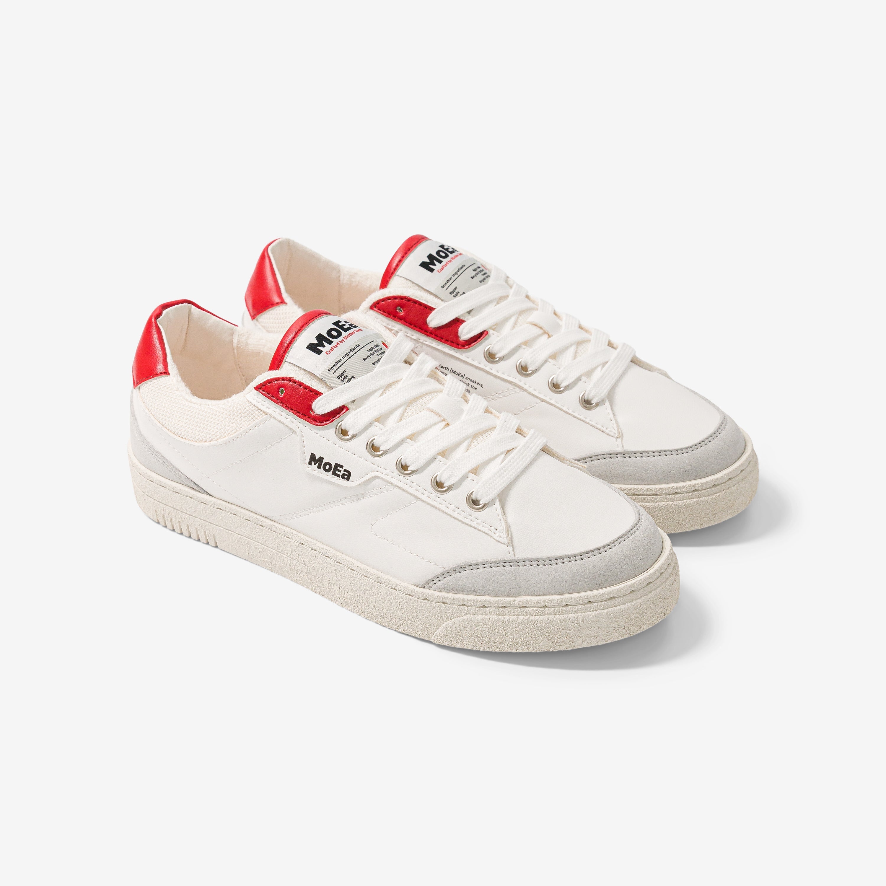 Ein Paar weiße Sneaker mit roten Akzenten an der Ferse und der Zunge, hellgrauen Details an der Spitze und der Sohle sowie dem MoEa-Branding an der Seite und der Zunge auf weißem Hintergrund.