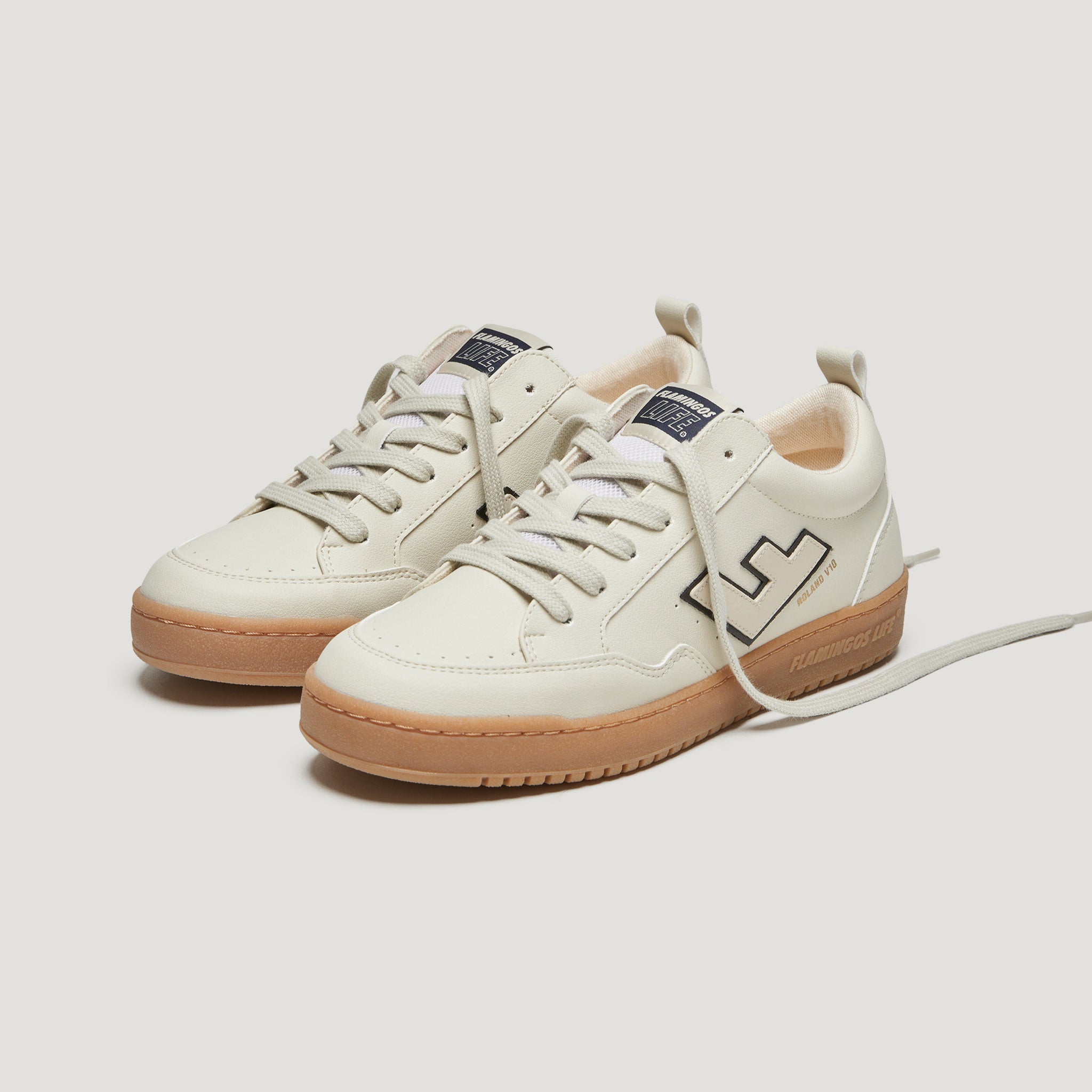 Weiße Sneaker mit brauner Sohle und Schnürsenkeln auf weißem Hintergrund.