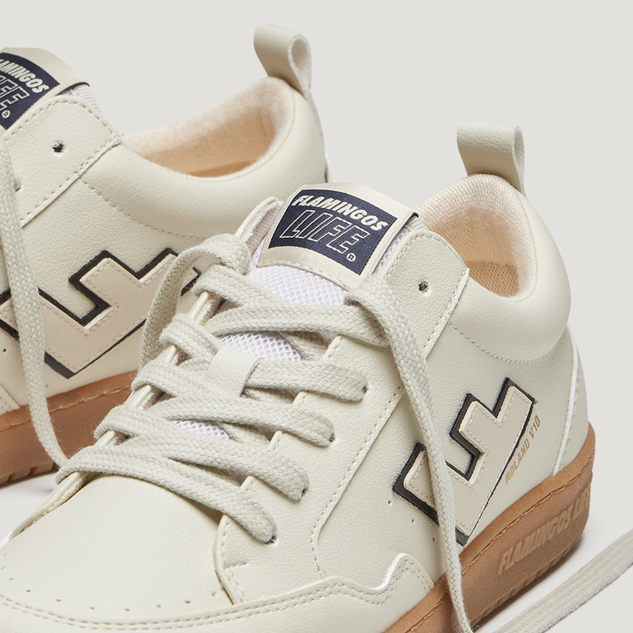 Beige Sneaker mit cremefarbenen Schnürsenkeln und brauner Sohle, mit "Flamingos Life"-Logo auf der Lasche.