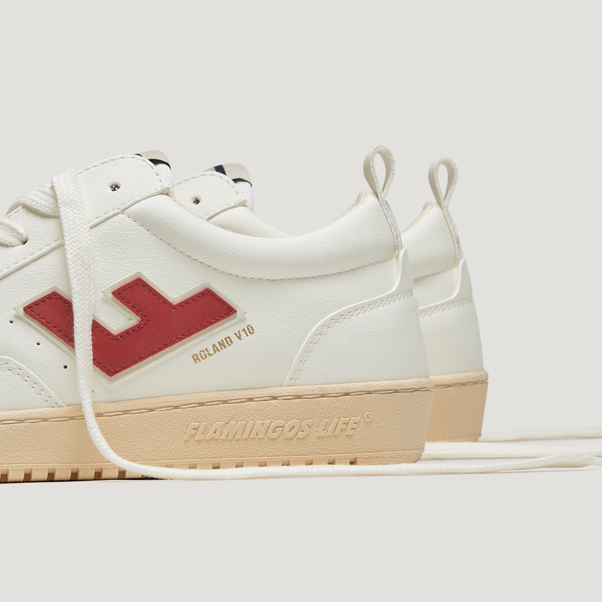 Weiße Sneaker mit roten Details und der Aufschrift „Flamingos Life“ an der Sohle, auf neutralem Hintergrund.