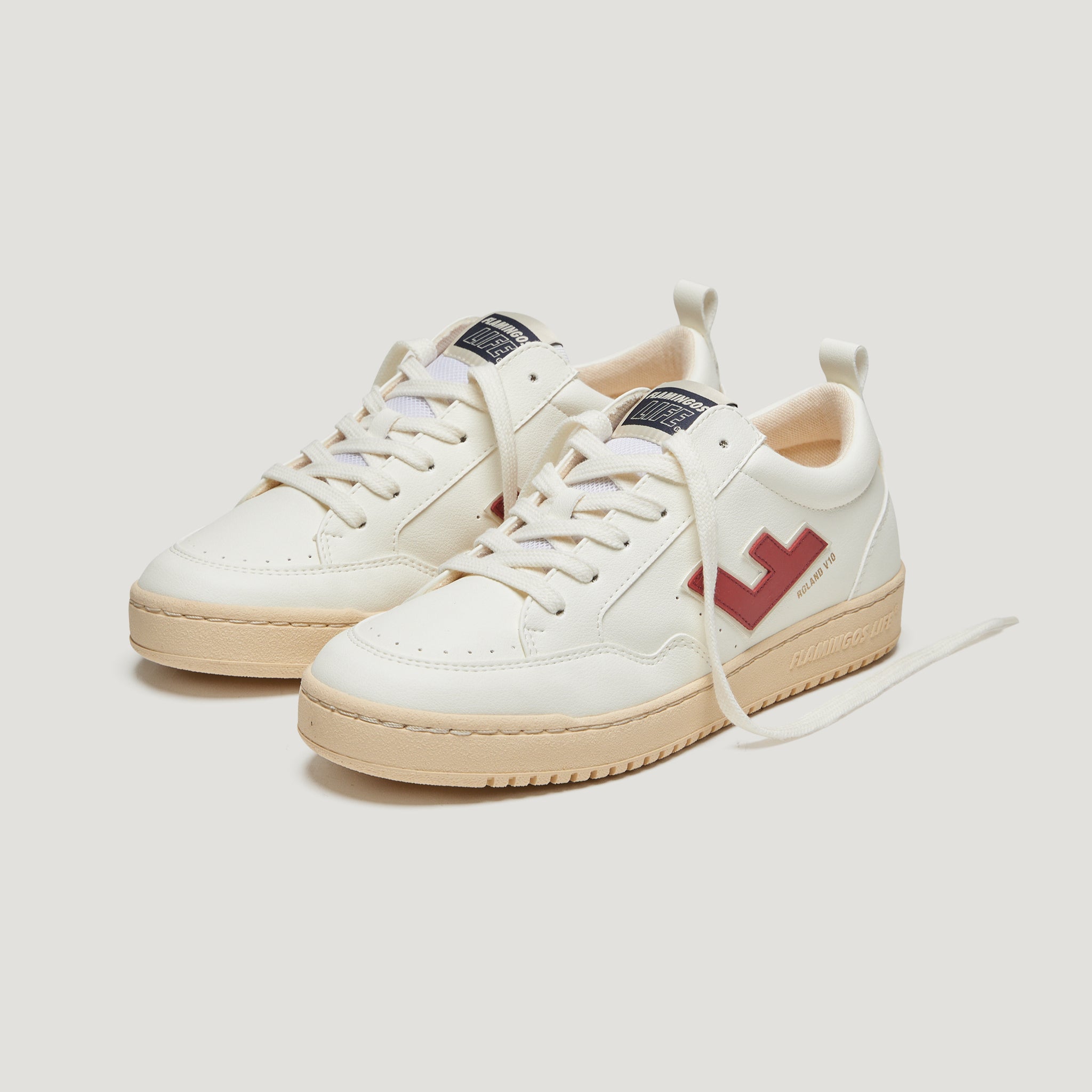 Weiße Sneakers mit beigefarbener Sohle und rotem Seitenlogo auf hellem Hintergrund.