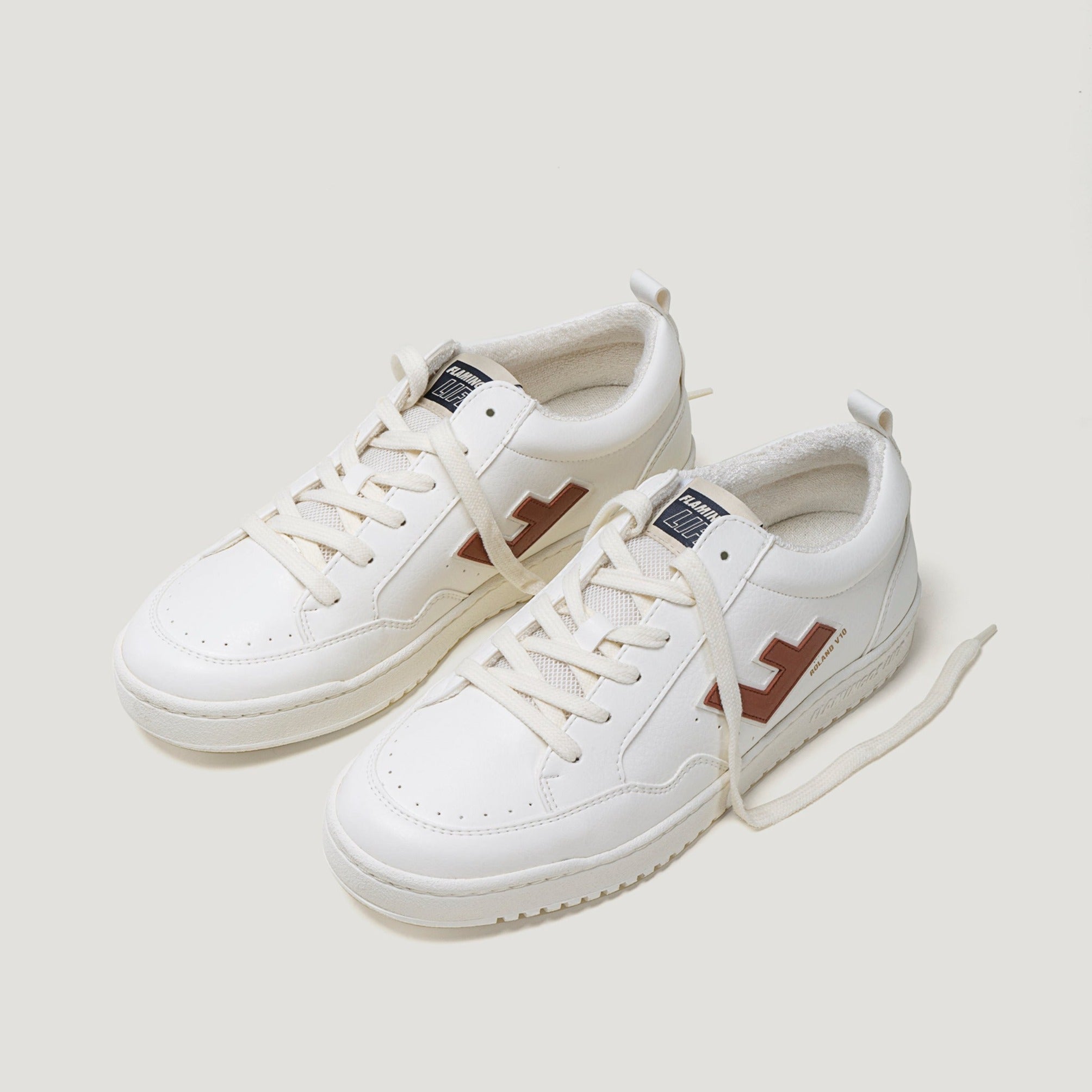 Weiße Turnschuhe mit braunen Details und weißen Schnürsenkeln auf neutralem Hintergrund.