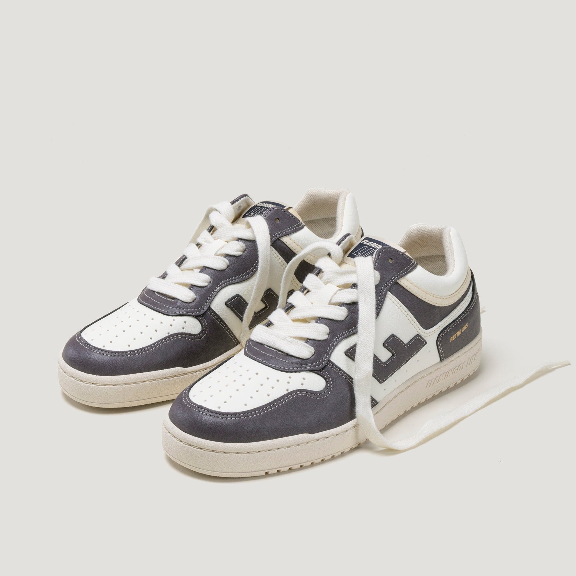 Weiße Turnschuhe mit dunkelblauen Akzenten und weißen Schnürsenkeln auf weißem Hintergrund.