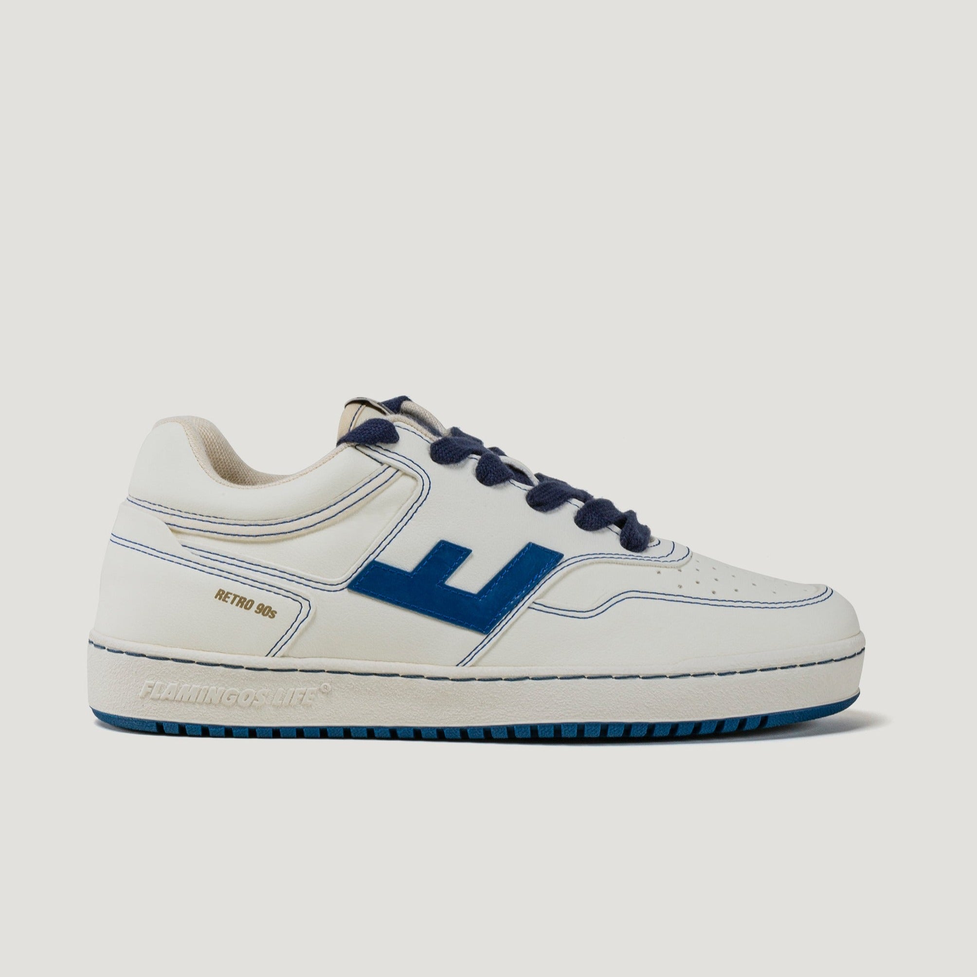 Weißer Sneaker mit blauen Akzenten und Schnürsenkeln, Seitenaufdruck "RETRO 90s" und Marke auf der Sohle.