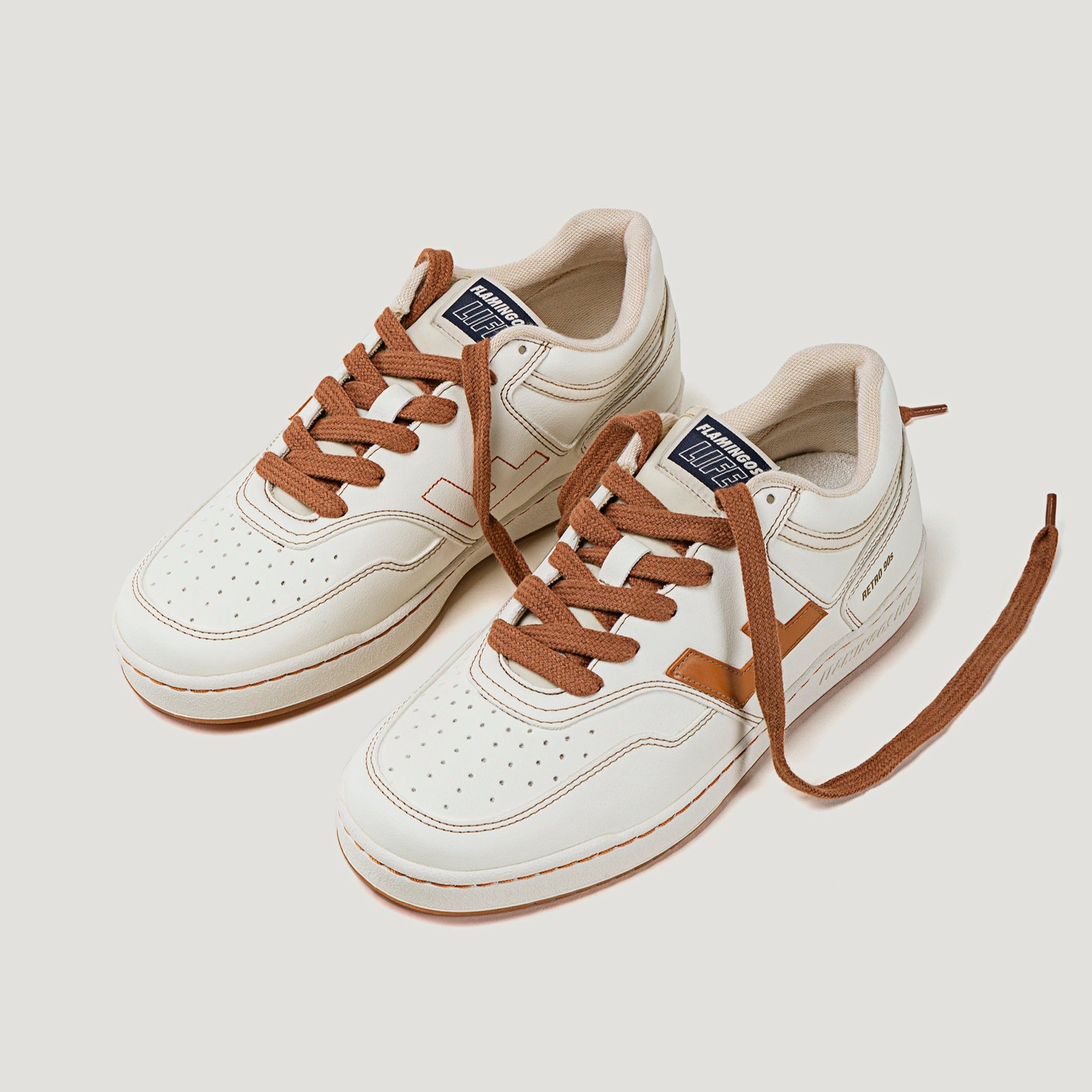 Weiße Sneaker mit braunen Schnürsenkeln und Akzenten, auf hellem Hintergrund dargestellt.