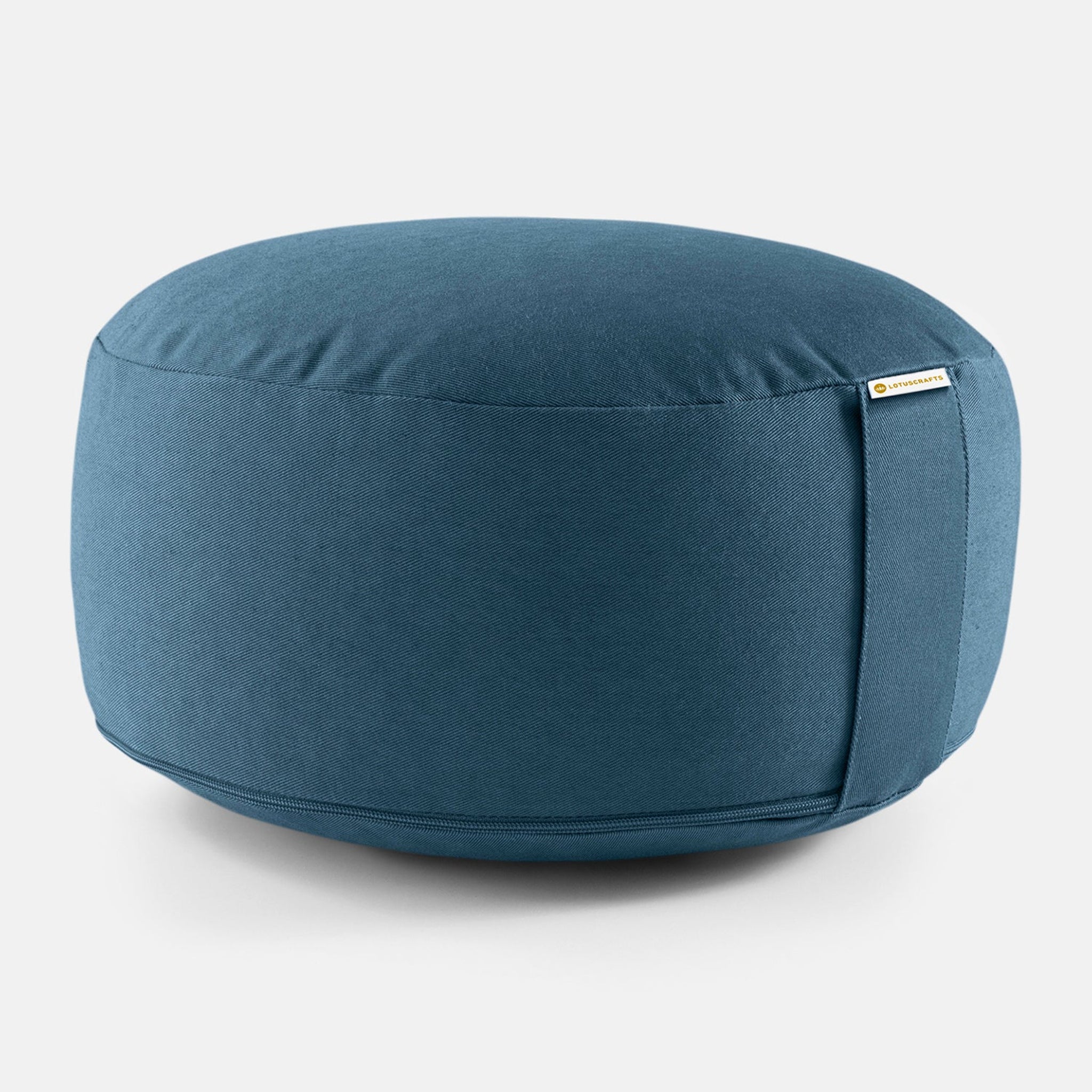 Runder, blauer Sitzpouf mit glatter Oberfläche und kleinem Schildchen an der Seite, vor weißem Hintergrund.