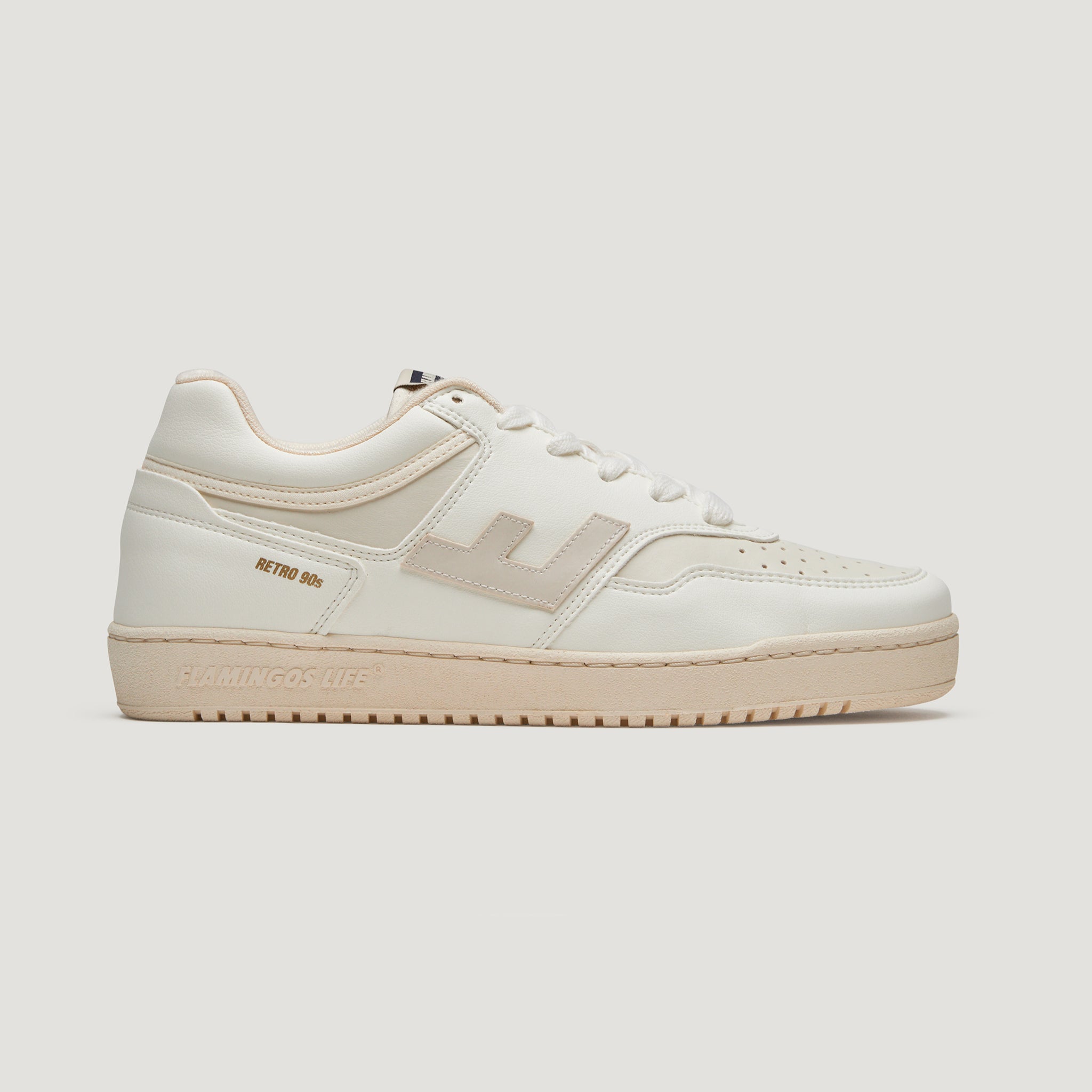 Weiße Sneaker im Retrolook mit cremefarbenen Akzenten und perforierter Zehenkappe vor einem weißen Hintergrund.