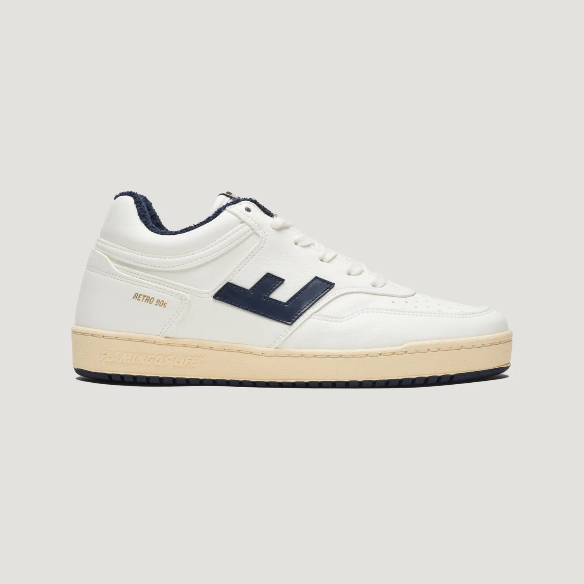 Weißer Sneaker im Retro-Stil mit schwarzem Logo und beigefarbener Sohle auf grauem Hintergrund.