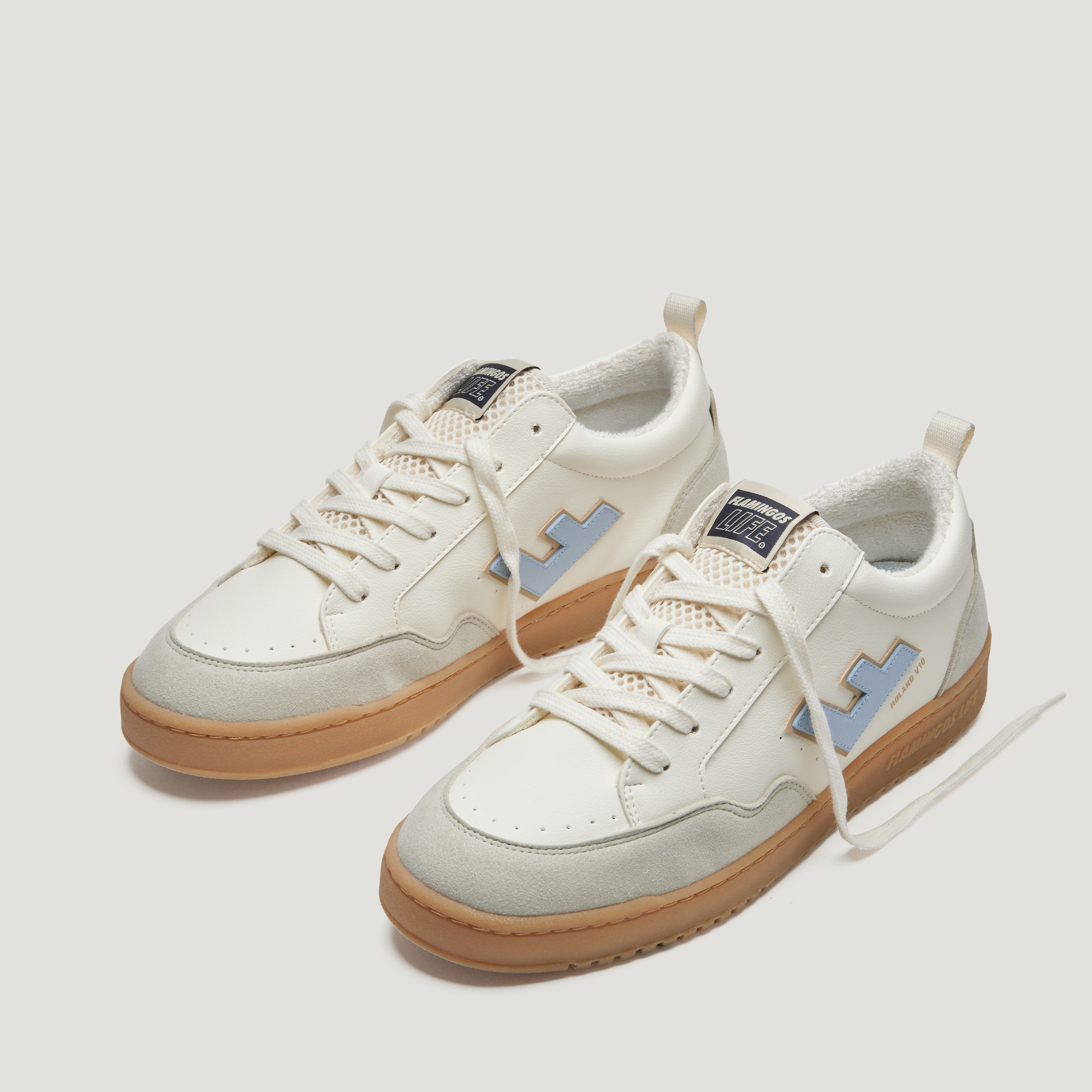 Weiße Sneaker mit hellblauen Akzenten und brauner Sohle, auf weißem Hintergrund fotografiert.