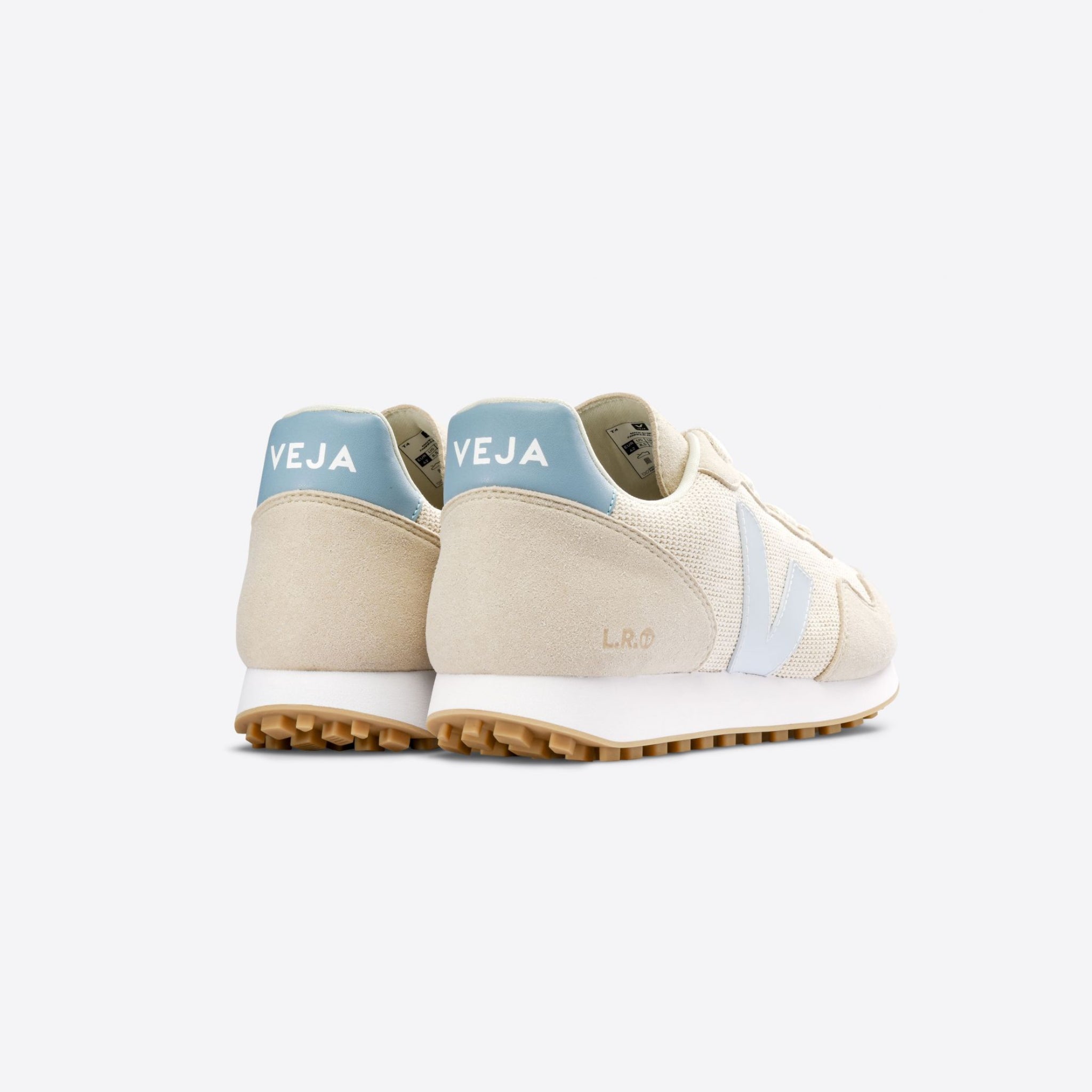Beige Turnschuhe mit blauer Ferse und weißem Logo auf der Seite, von hinten gezeigt, auf weißem Hintergrund.