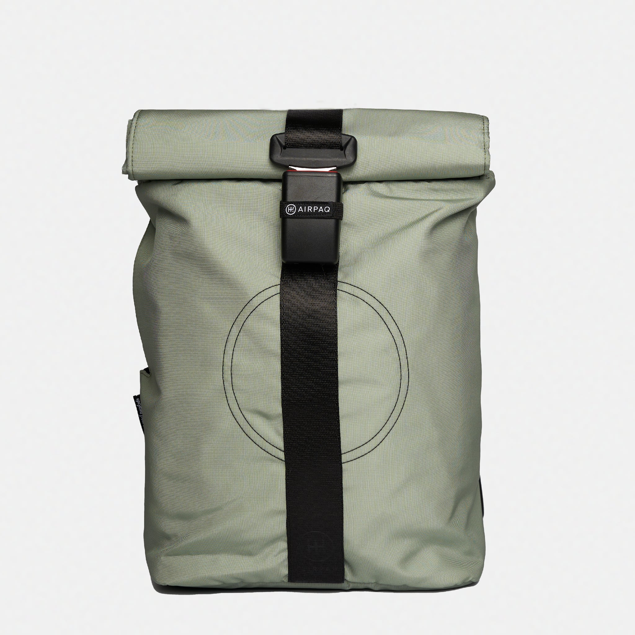 Hellgrauer Rolltop-Rucksack mit schwarzem, vertikalem Riemen und Schnallenverschluss. Auf der Vorderseite befindet sich ein kreisförmiges, genähtes Muster und ein kleines AIRPAQ-Label in der Nähe der Schnalle.