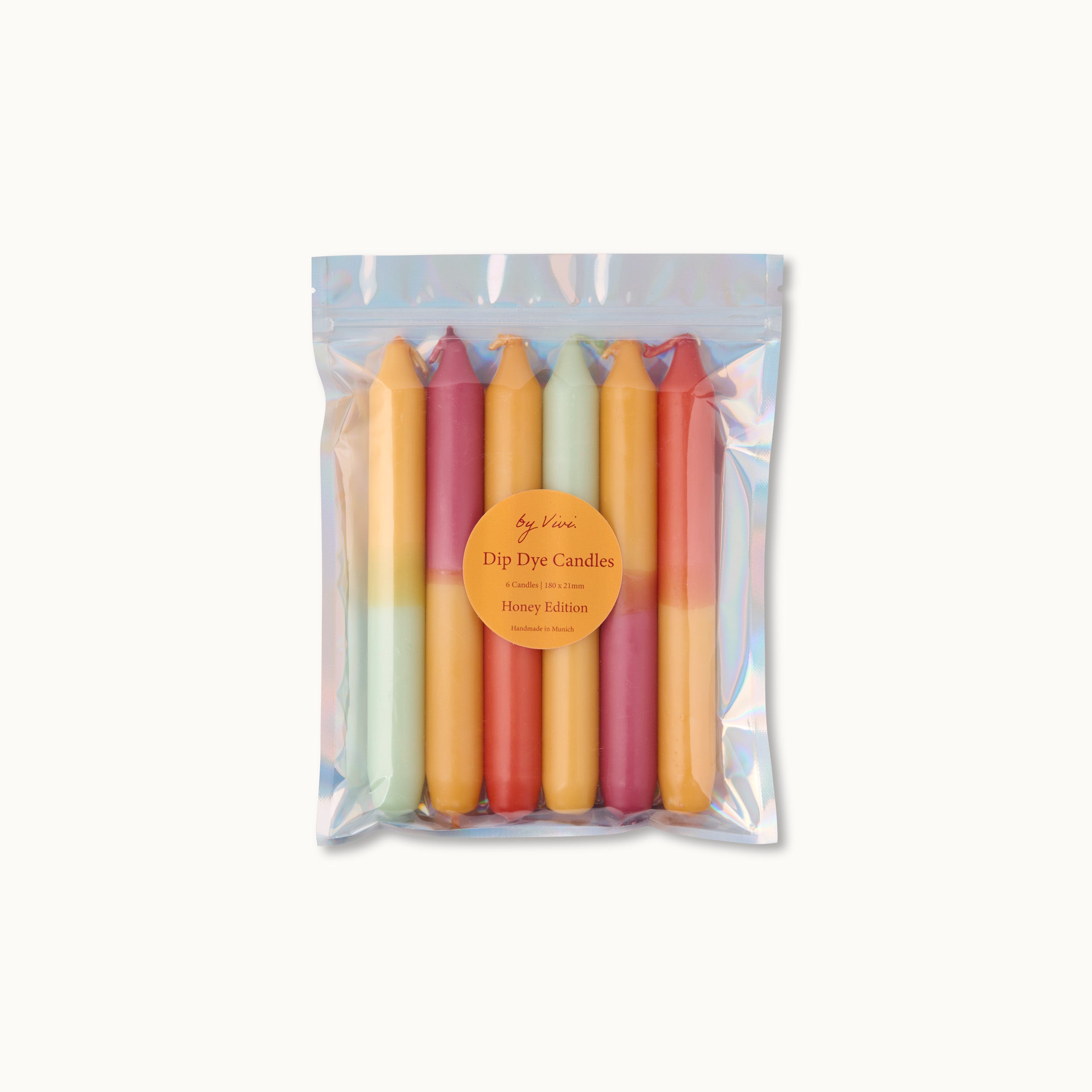 Ein wiederverschließbarer, durchsichtiger Beutel mit sechs bunten Dip-Dye-Kerzen in Gelb-, Grün-, Orange- und Rosatönen. Der Beutel hat ein rundes orangefarbenes Etikett mit der Aufschrift Dip Dye Candles, Honey Edition.