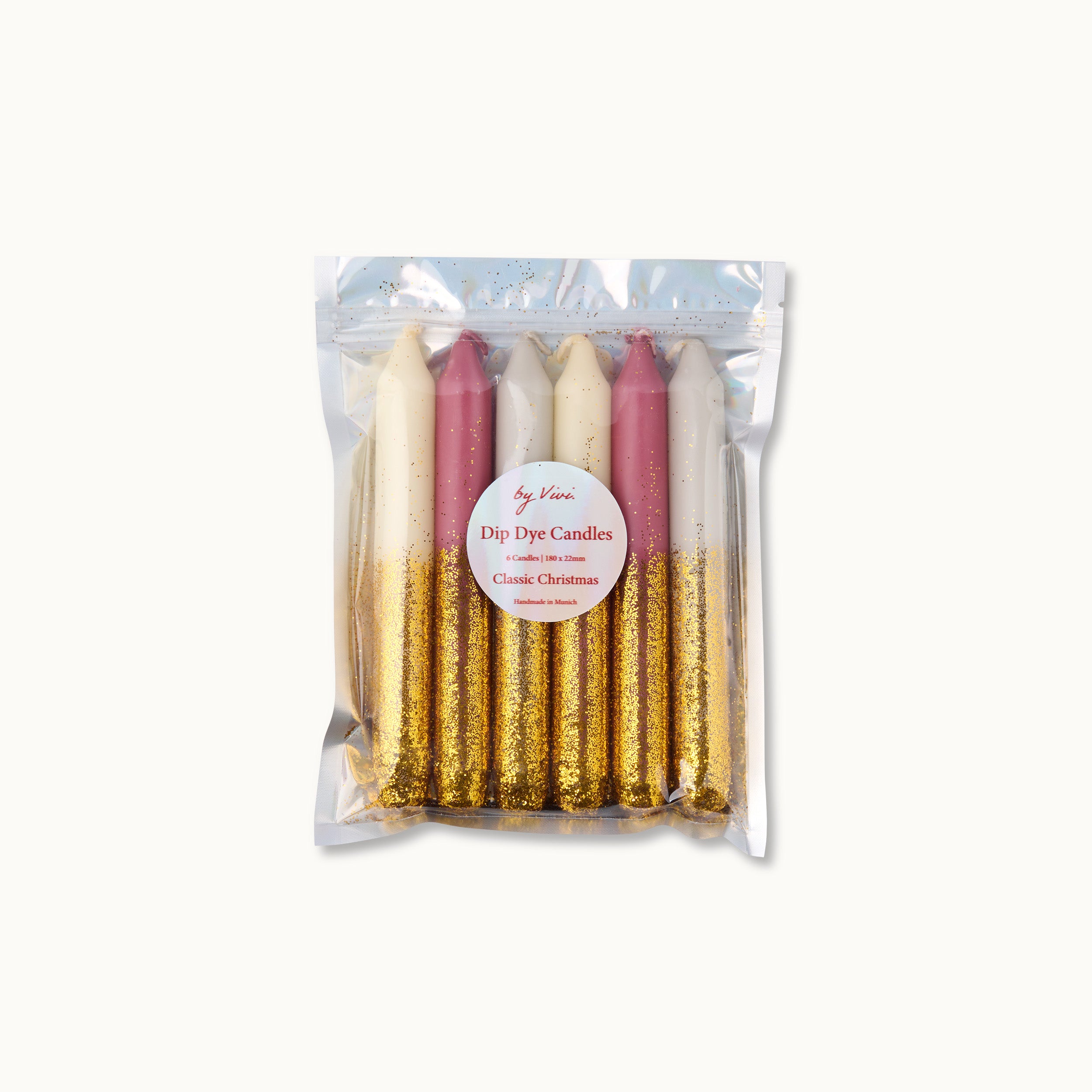 Eine durchsichtige Plastiktüte mit sechs Dip-Dye-Kerzen in Weiß, Rosa und Cremefarben, jede mit Goldglitter auf der unteren Hälfte. Auf einem Etikett steht "Dip Dye Candles - Classic Christmas".