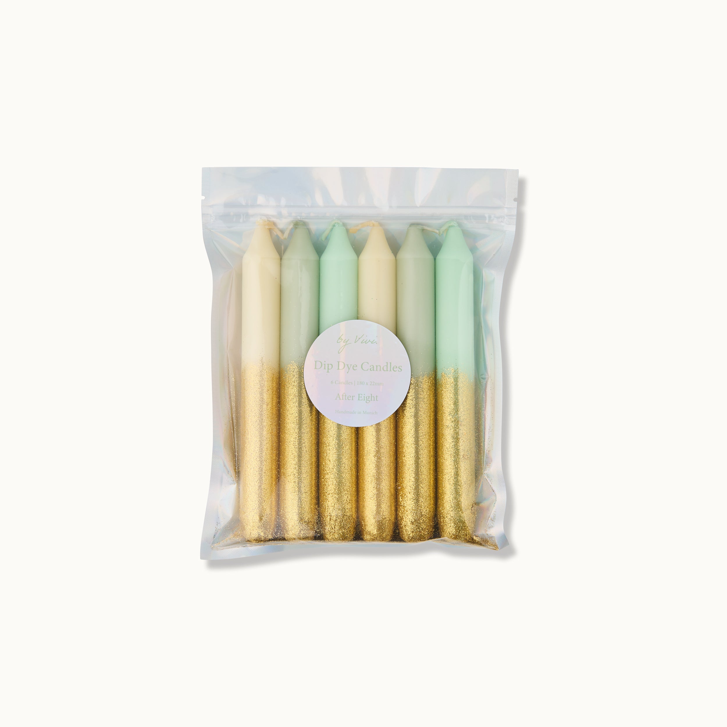 Eine durchsichtige Plastiktüte enthält sechs Dip-Dye-Kerzen in Creme-, Mintgrün- und Hellblautönen, wobei jede Kerze in der unteren Hälfte mit Goldglitter verziert ist. Ein rundes Etikett befindet sich auf der Vorderseite der Tüte.