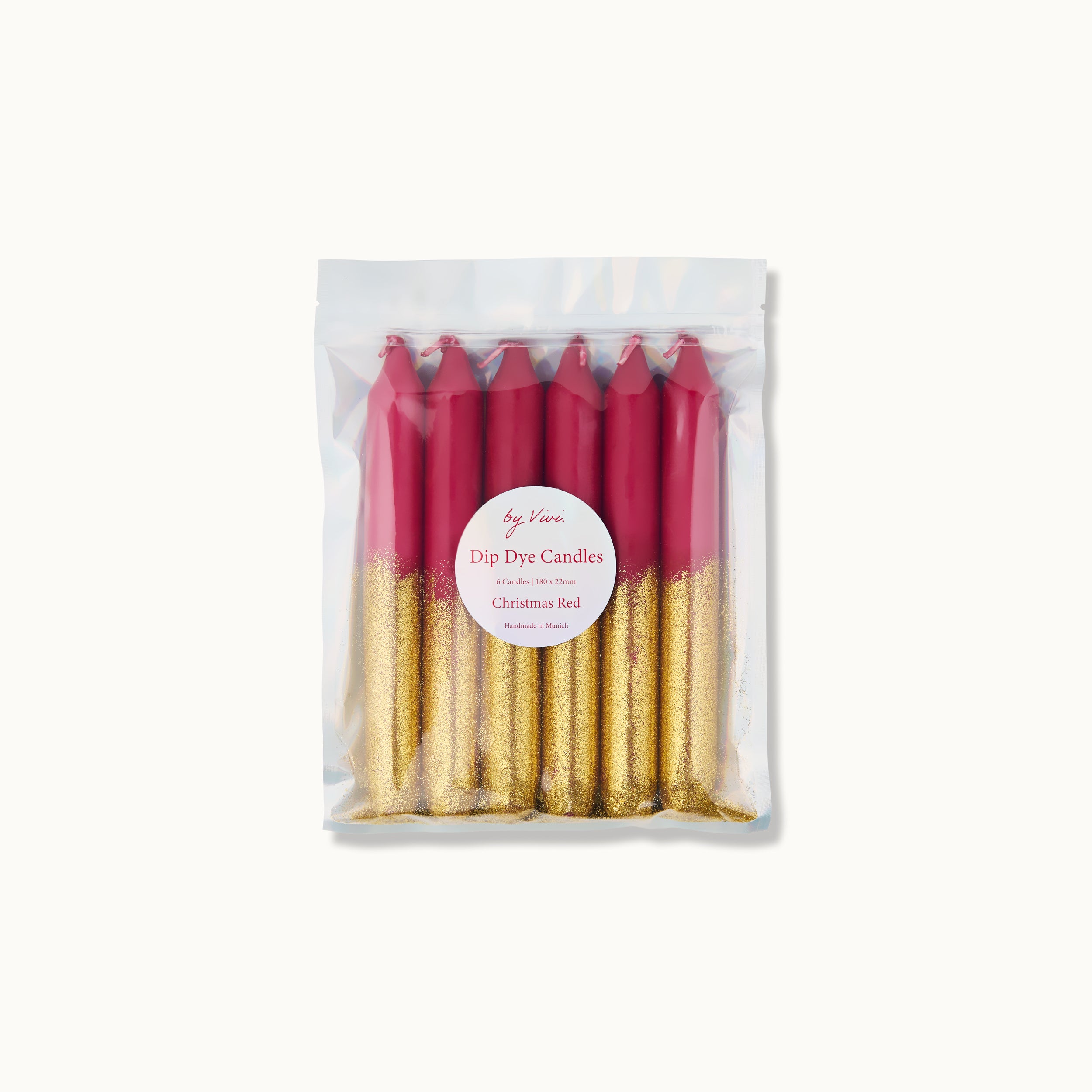 Eine durchsichtige Plastikverpackung enthält sechs aufrecht stehende rote und golden glitzernde Dip-Dye-Kerzen. Auf der Vorderseite befindet sich ein rundes weißes Etikett mit der Aufschrift "Dip Dye Candles - Christmas Red".