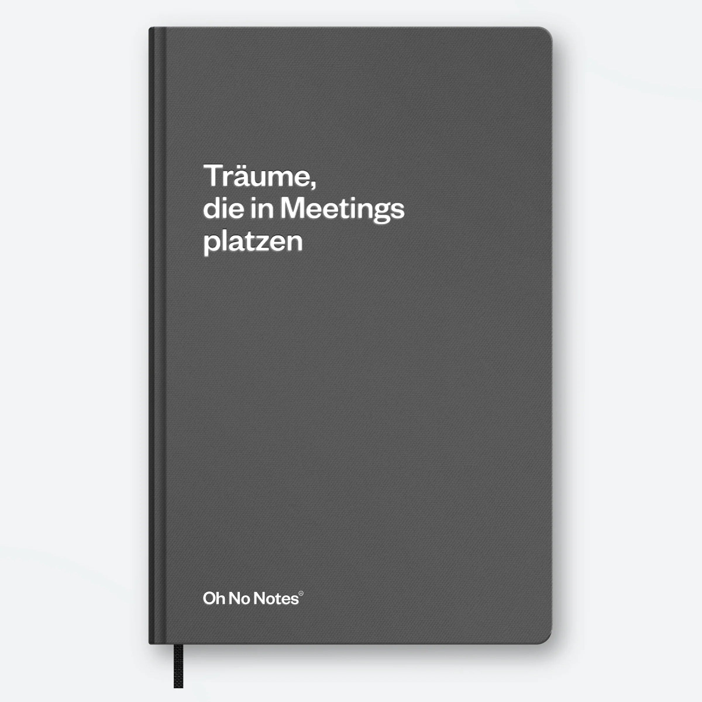 Ein graues Notizbuch mit dem deutschen Text Träume, die in Meetings platzen auf dem Umschlag in Weiß und Oh No Notes® in der rechten unteren Ecke. Unten ist ein Lesezeichen mit schwarzem Band zu sehen.