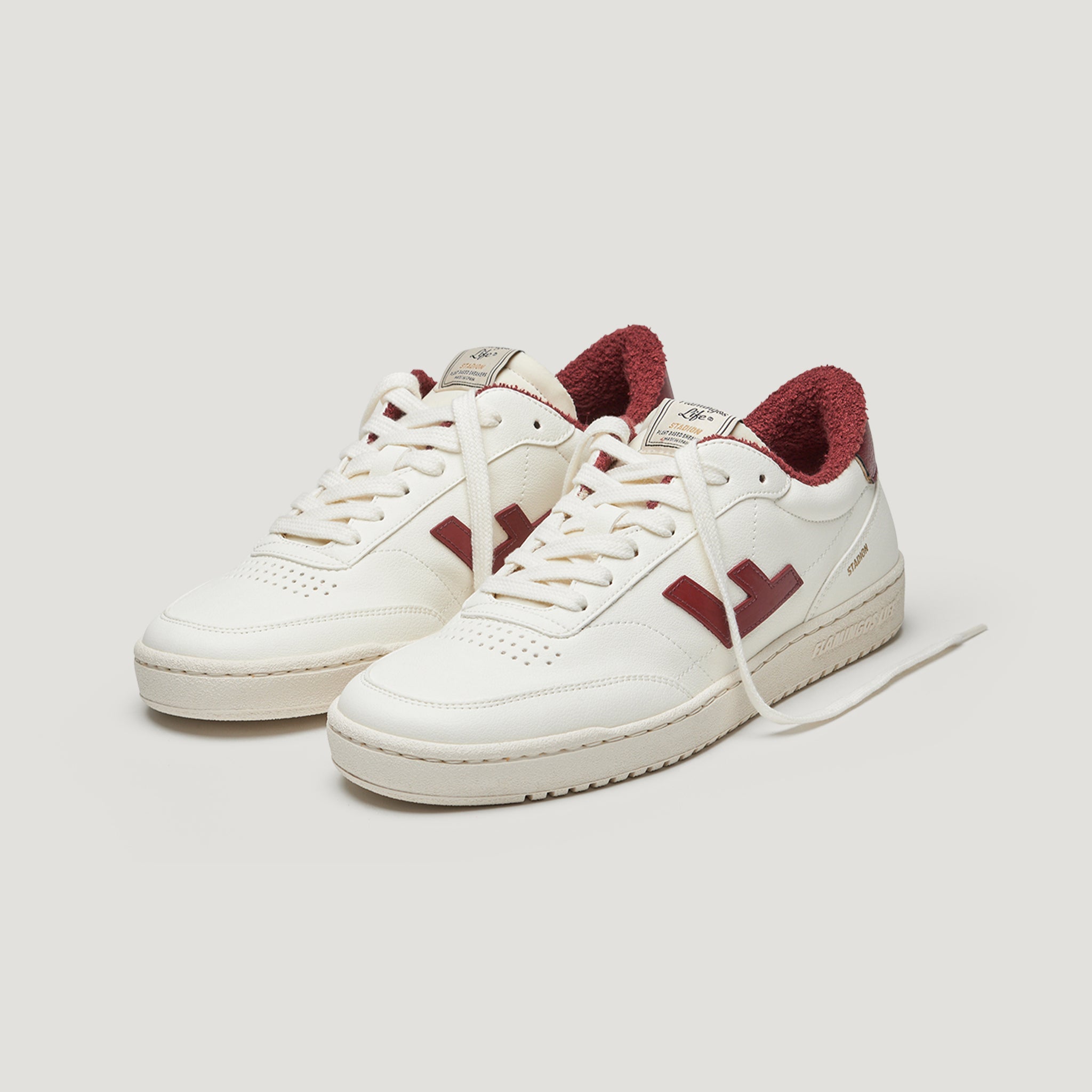 Weiße Sneaker mit roten Akzenten und rot gefüttertem Innenbereich auf einem neutralen Hintergrund.