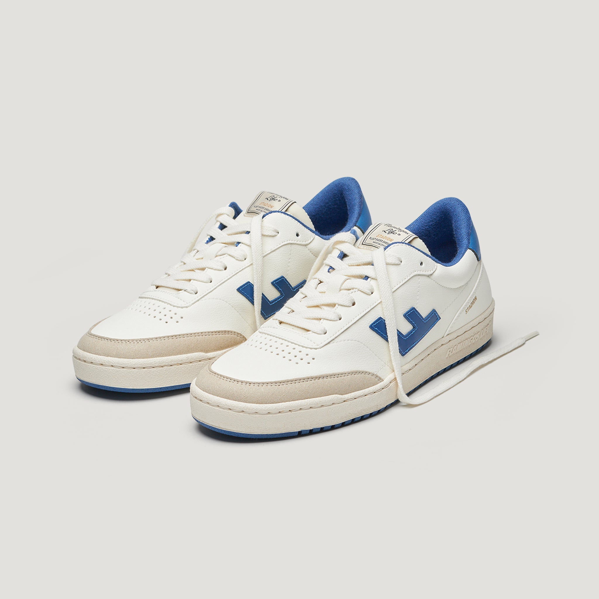 Weiße Sneaker mit blauen Details und einer cremefarbenen Sohle auf hellem Hintergrund.