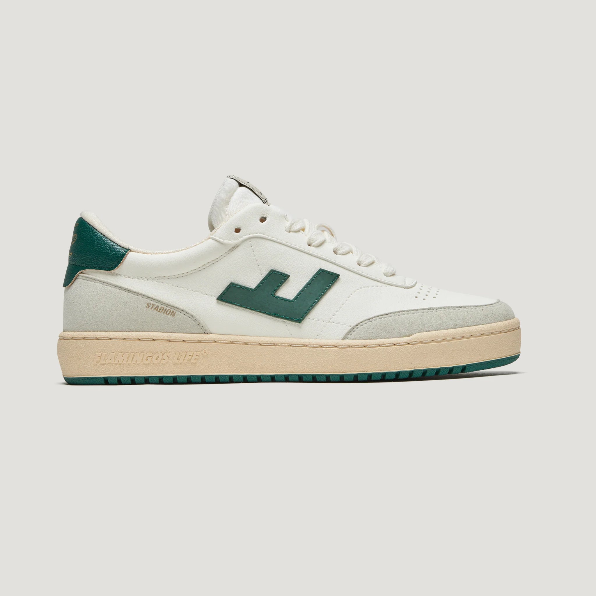 Weißer Sneaker mit grünem Logo, grüner Ferse und beigem Rand auf einer beigen, grünen Sohle.