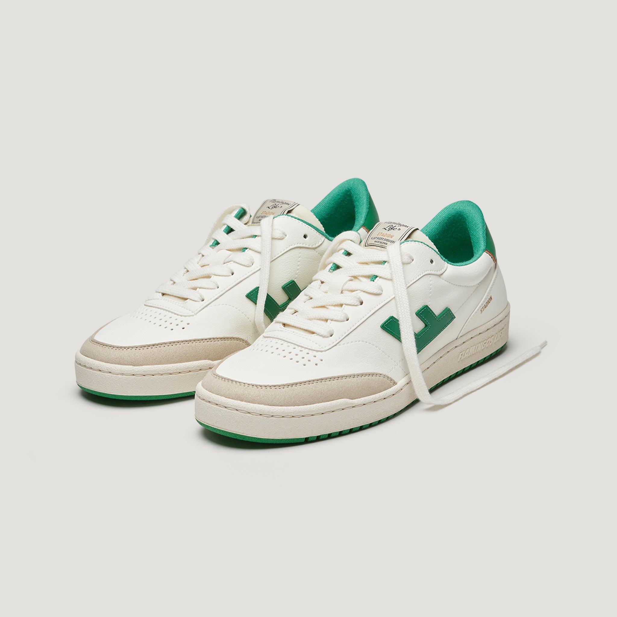 Weiße Sneakers mit grünen Details und grünem Innenfutter, schräg von vorne fotografiert.