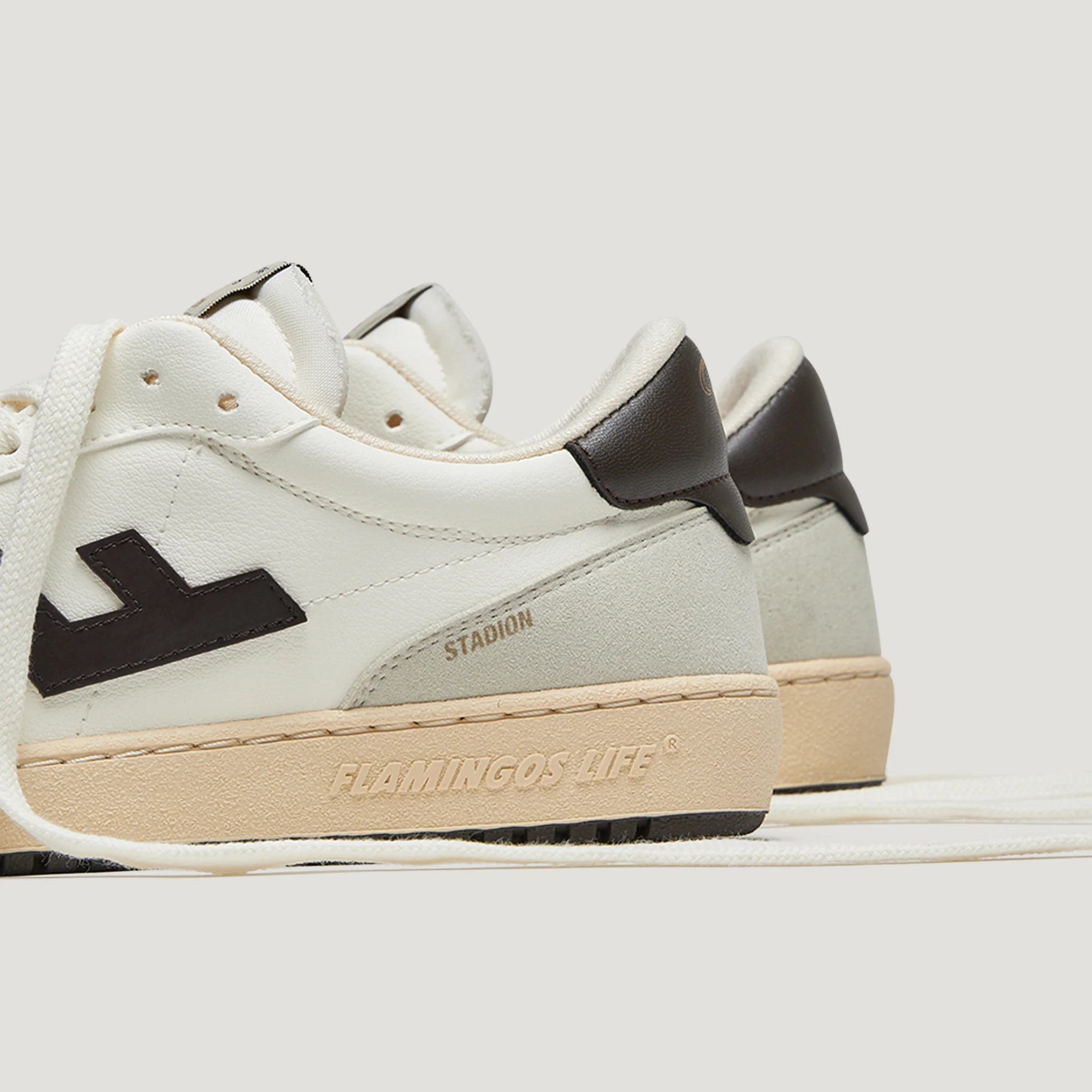 Weiße Sneaker mit braunen Details und beiger Sohle, seitlich beschriftet mit "Flamingos Life" und "Stadion".