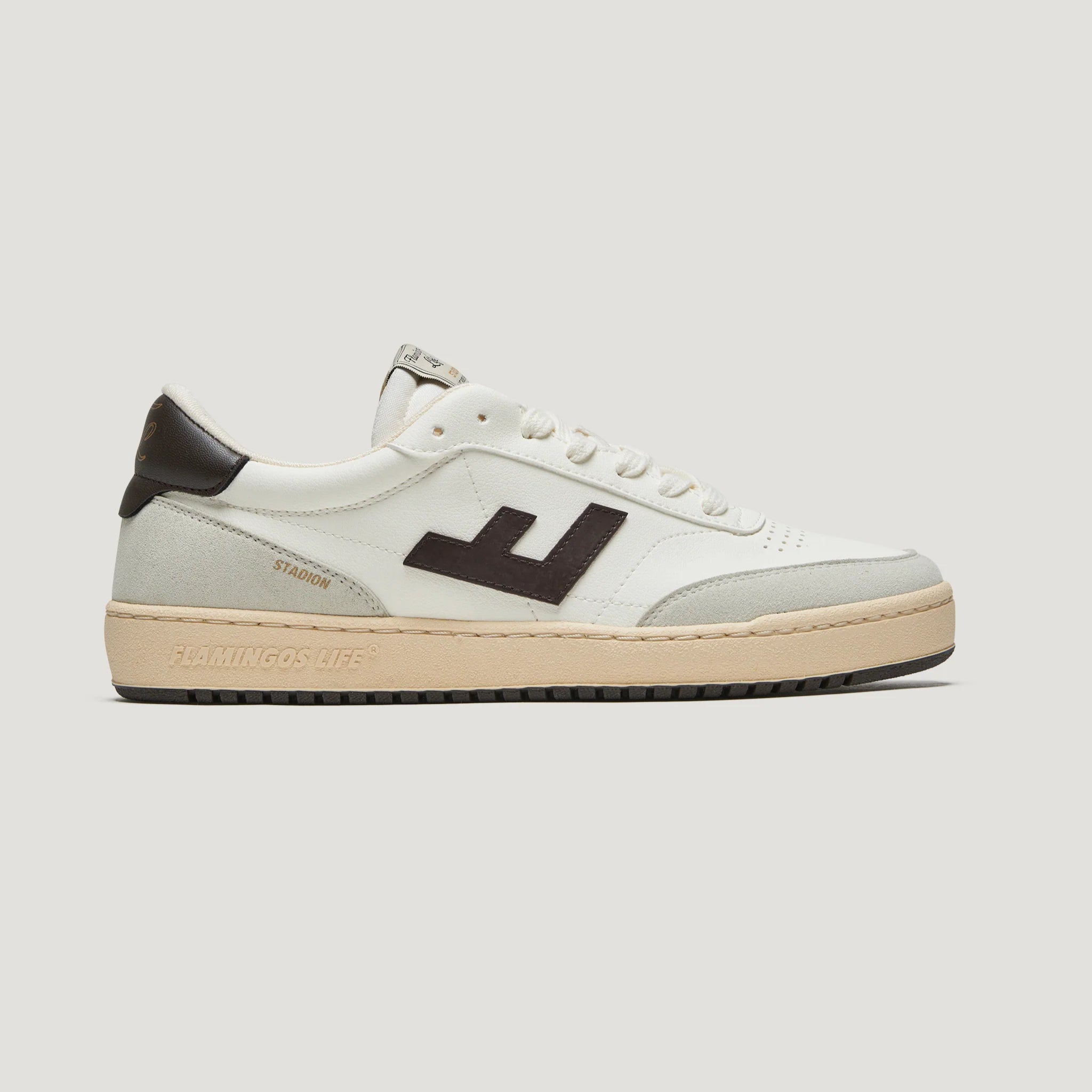 Weißer Sneaker mit schwarzem Logo und cremefarbener Sohle. Im Seitenprofil auf neutralem Hintergrund dargestellt.