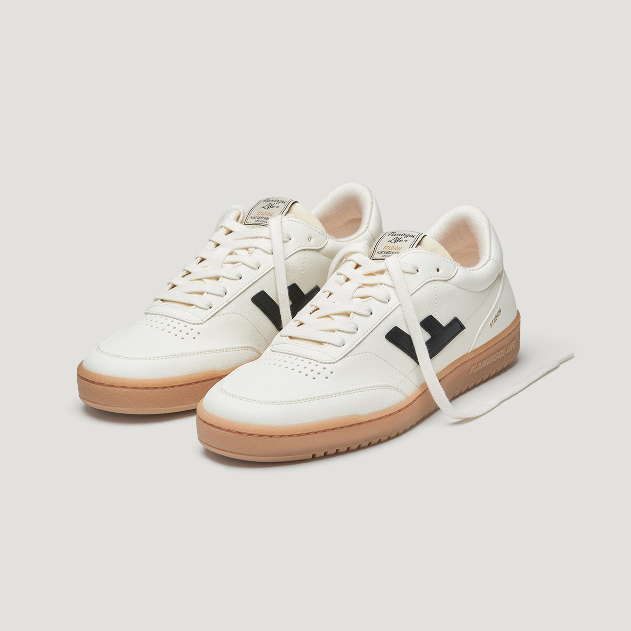 Weiße Sneaker mit hellbrauner Sohle und schwarzen Details, nebeneinander aufgestellt, auf hellem Hintergrund.