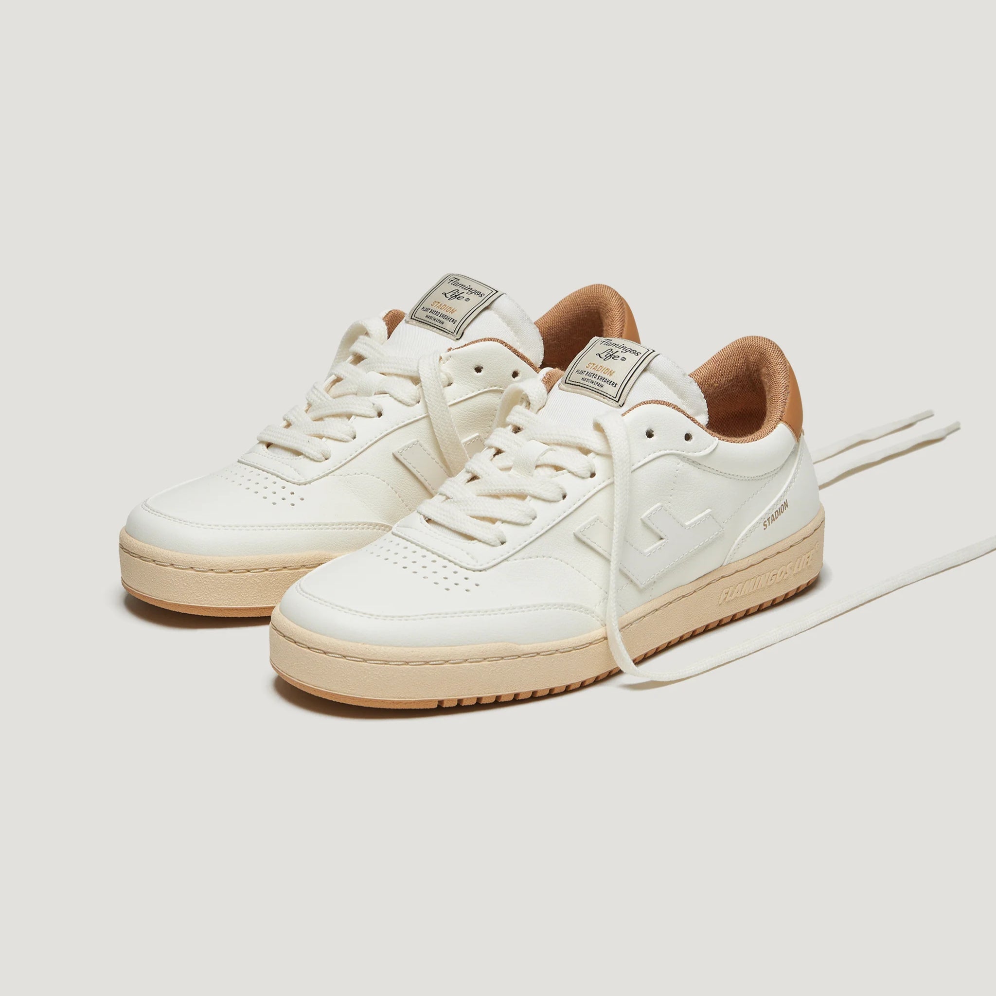 Weiße Sneaker mit beiger Sohle und braunem Innenfutter, auf weißem Hintergrund platziert.