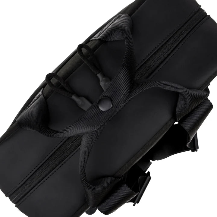 Schwarzer Seesack mit zwei Henkeln, die mit einem Druckknopf gesichert sind, sichtbaren Reißverschlüssen und verstellbaren Schulterriemen, von oben vor weißem Hintergrund fotografiert.