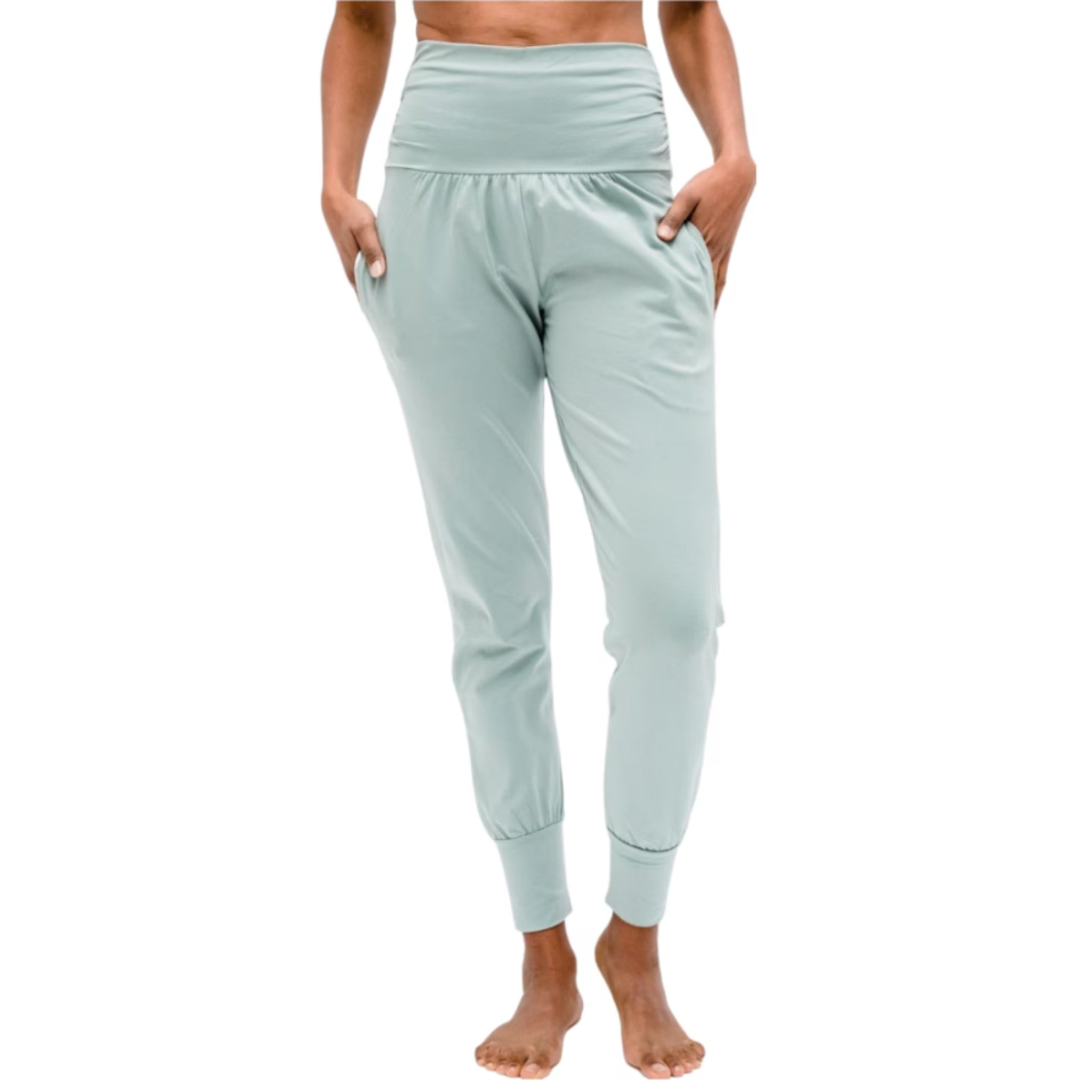 Person in mintgrüner Yogahose mit hohem Bund und Taschen steht barfuß.