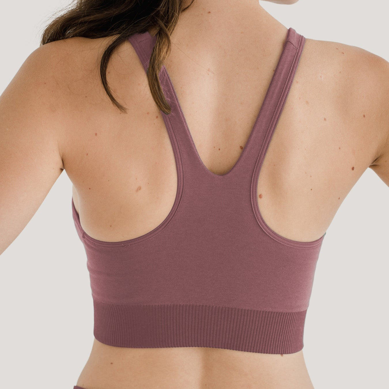 Rückansicht einer Person in einem lila Sport-BH mit Racerback-Design.
