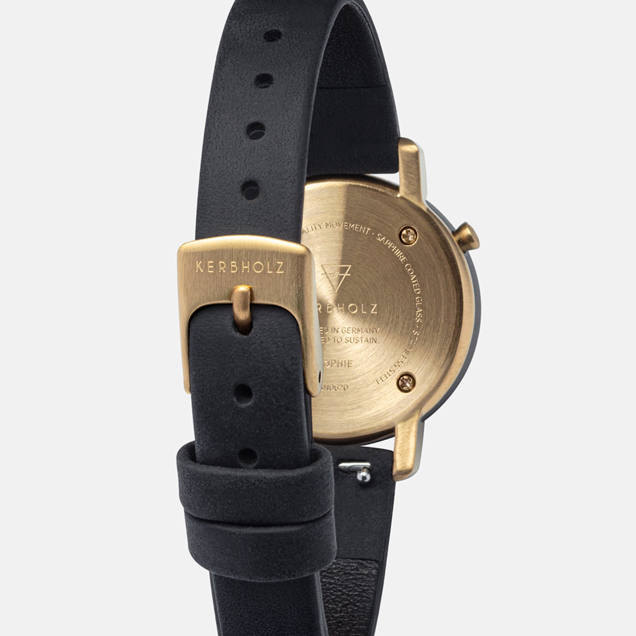 Goldene Rückseite einer Uhr mit schwarzem Lederarmband, sichtbar mit der Aufschrift „Kerbholz“.