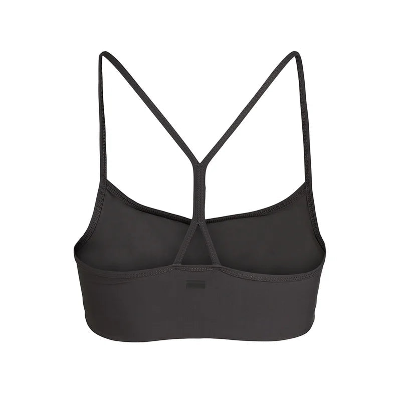 Ein schwarzer Sport-BH in Rückenansicht mit dünnen Trägern, die ein Racerback-Design auf weißem Grund bilden.