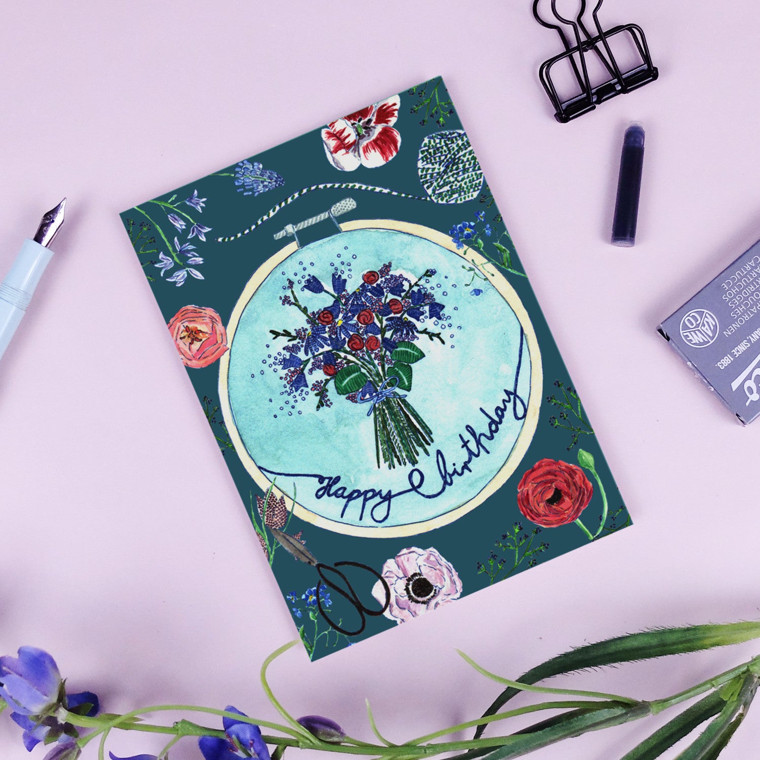 Geburtstagskarte mit Blumenstrauß und der Aufschrift "Happy Birthday", umgeben von Blumenmotiven auf rosa Hintergrund.