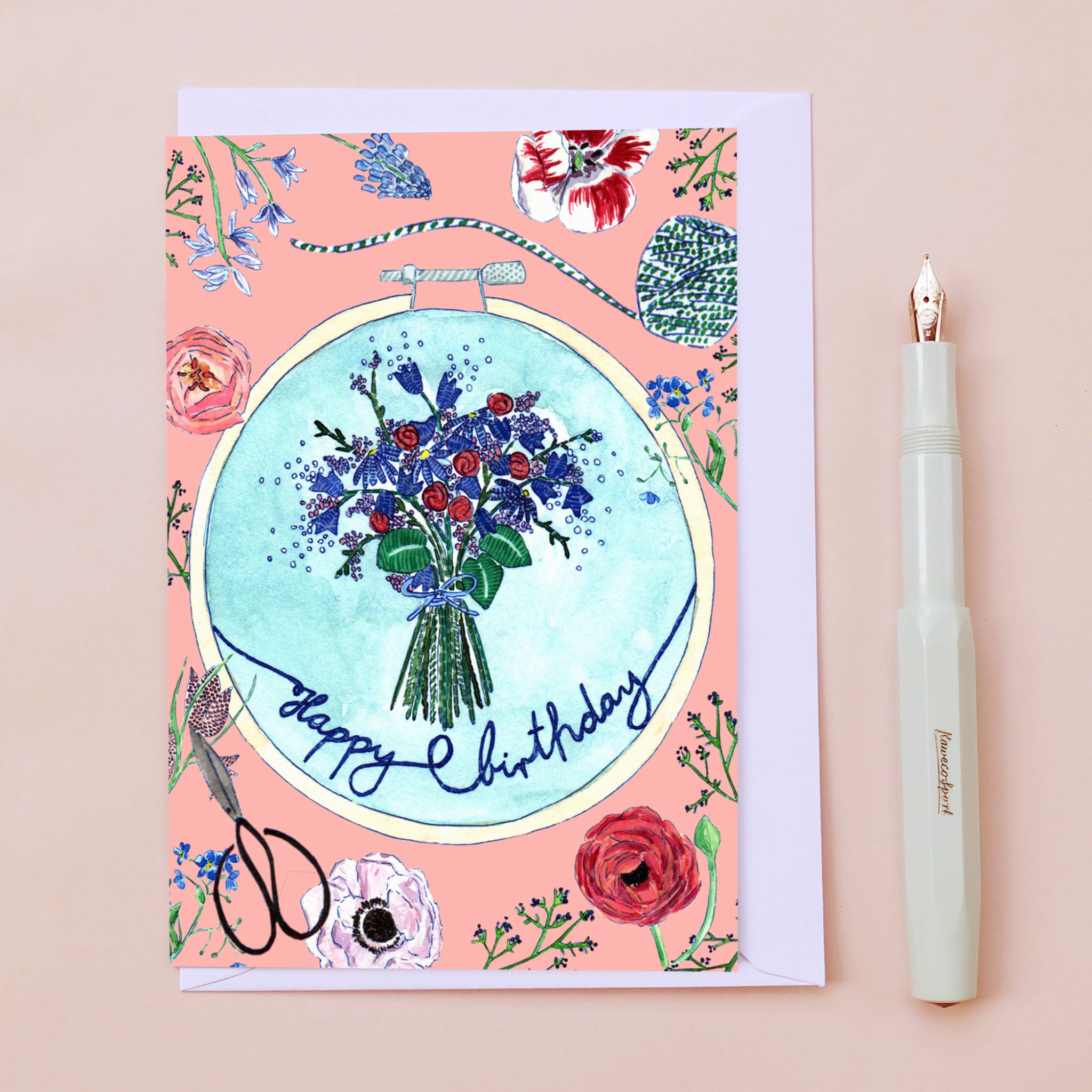 Geburtstagskarte mit buntem Blumenstrauß und Schriftzug "Happy Birthday", daneben ein Füllfederhalter.