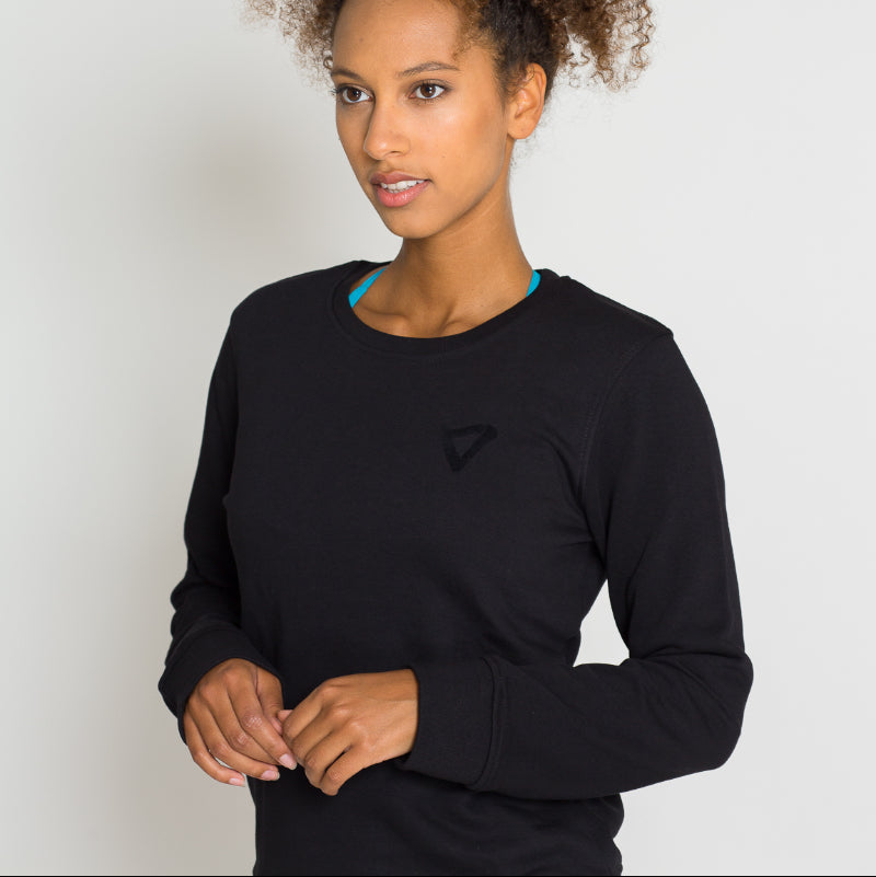 Frau in schwarzem Langarmshirt vor weißem Hintergrund.