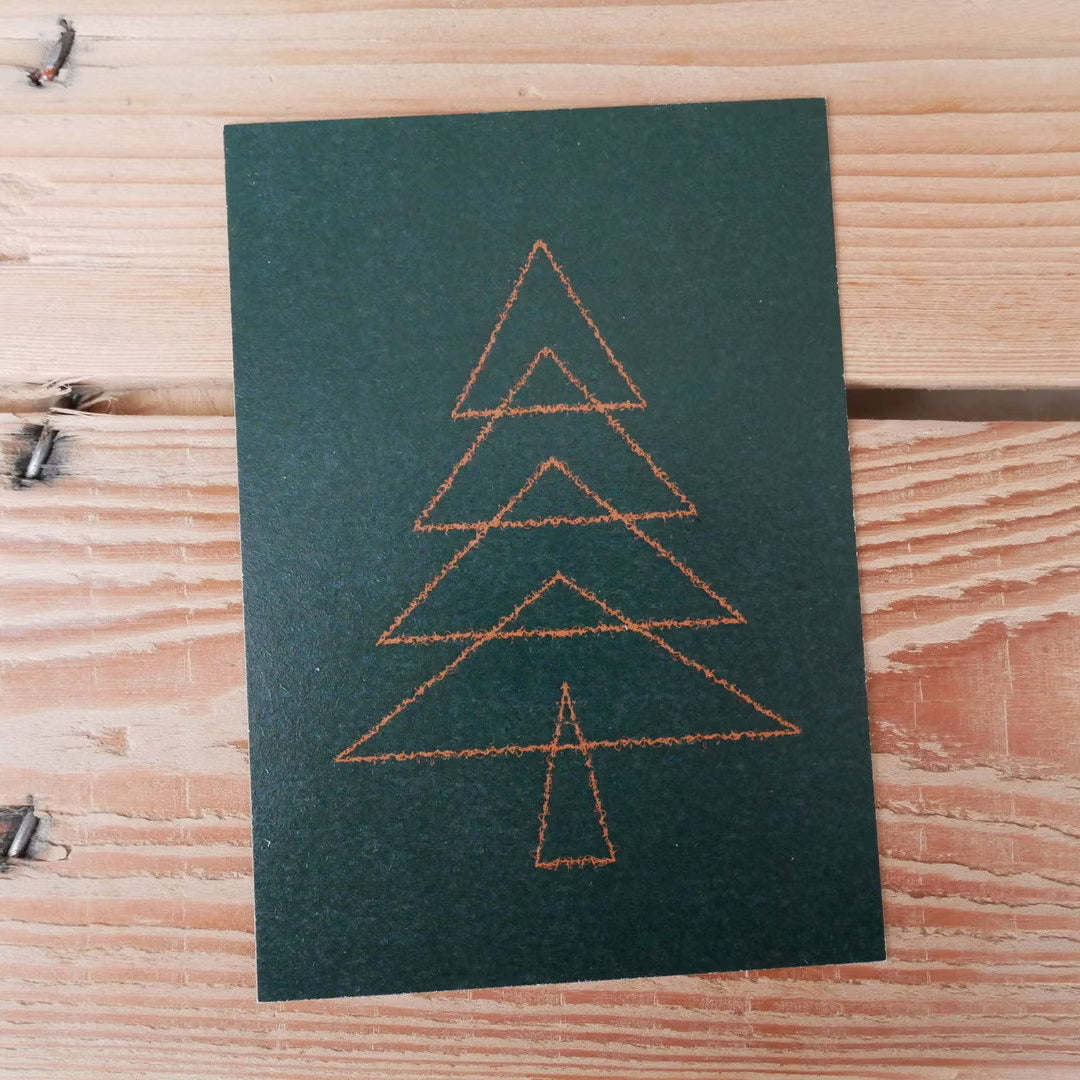 Karte mit einem minimalistischen, skizzierten Weihnachtsbaum in Dreiecksform auf schwarzem Hintergrund, auf Holztisch.
