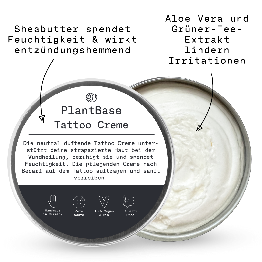 Eine offene Dose PlantBase Tattoo Creme mit einer weißen, cremigen Textur. Das Etikett hebt die beruhigende, feuchtigkeitsspendende, vegane und grausamkeitsfreie Formel hervor und enthält einen deutschen Text über die Verwendung zur Tattoo-Nachsorge.