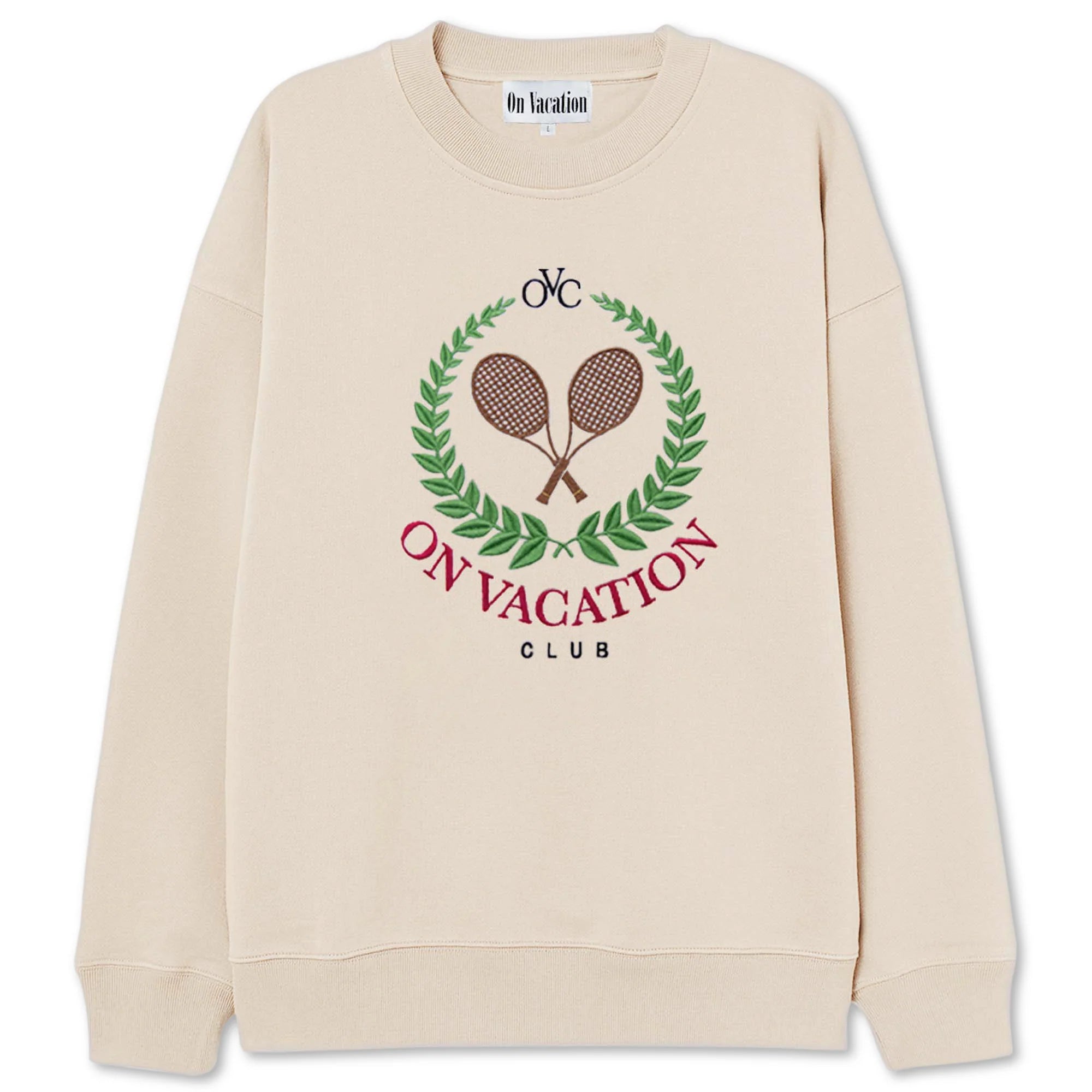Beiger Pullover mit der Aufschrift "ON VACATION CLUB" und zwei gekreuzten Tennisschlägern in einem Blätterkranz.