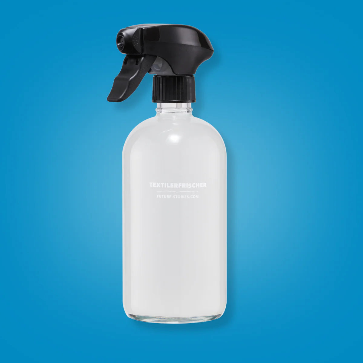 Eine durchsichtige Sprühflasche mit einer schwarzen Abzugsdüse, gefüllt mit einer weißen Flüssigkeit, ist vor einem einfarbig blauen Hintergrund abgebildet. Auf dem Etikett steht TEXTILERFRISCHER.