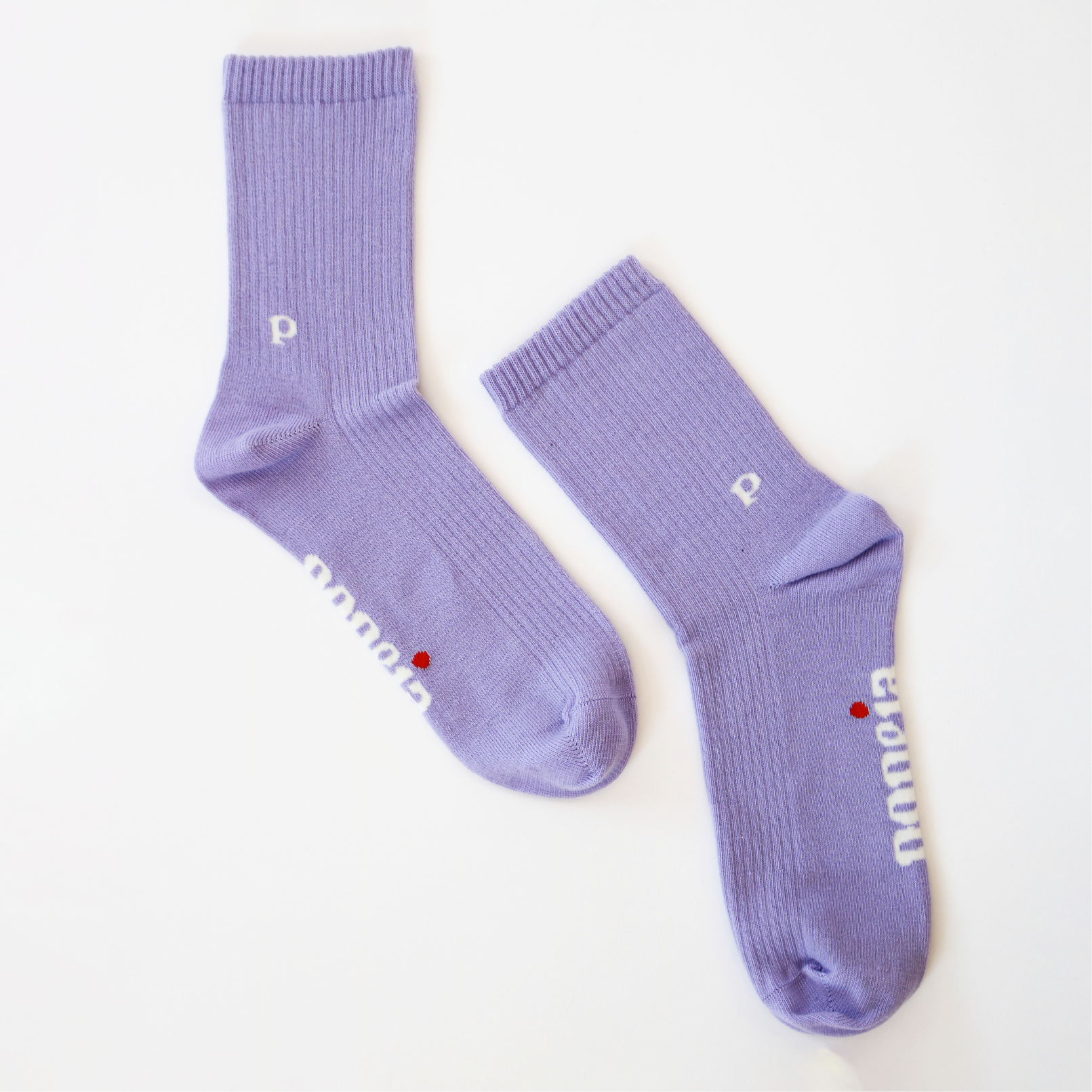 Lila Socken mit kleinen weißen Buchstaben und einem roten Punkt auf hellem Hintergrund.