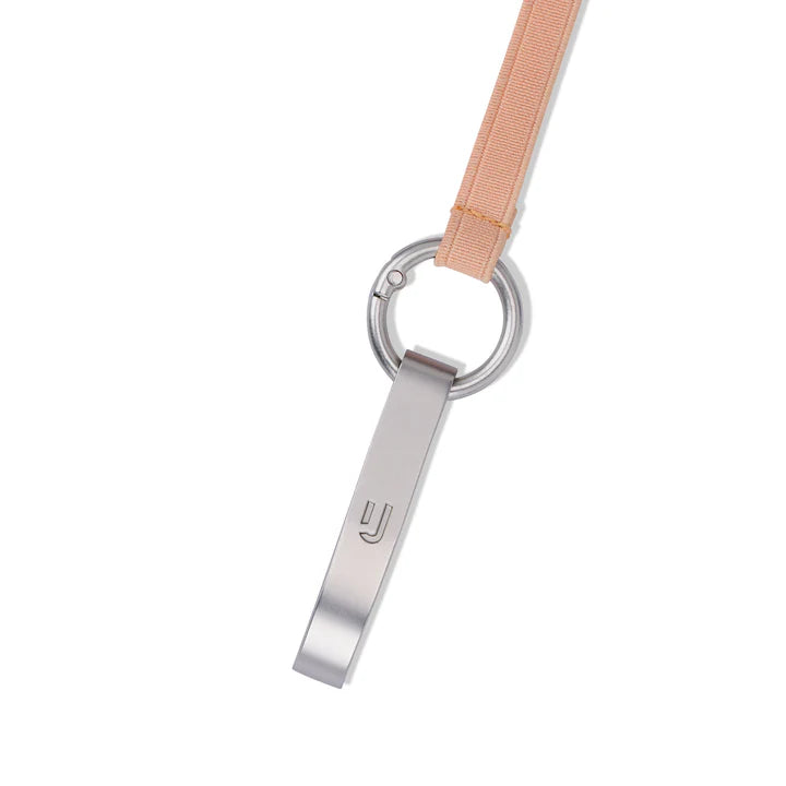 Eine silberne Metallpfeife mit minimalistischem Design hängt an einem pfirsichfarbenen Schlüsselband, das an einem runden Metallschlüsselring befestigt ist, vor einem weißen Hintergrund.