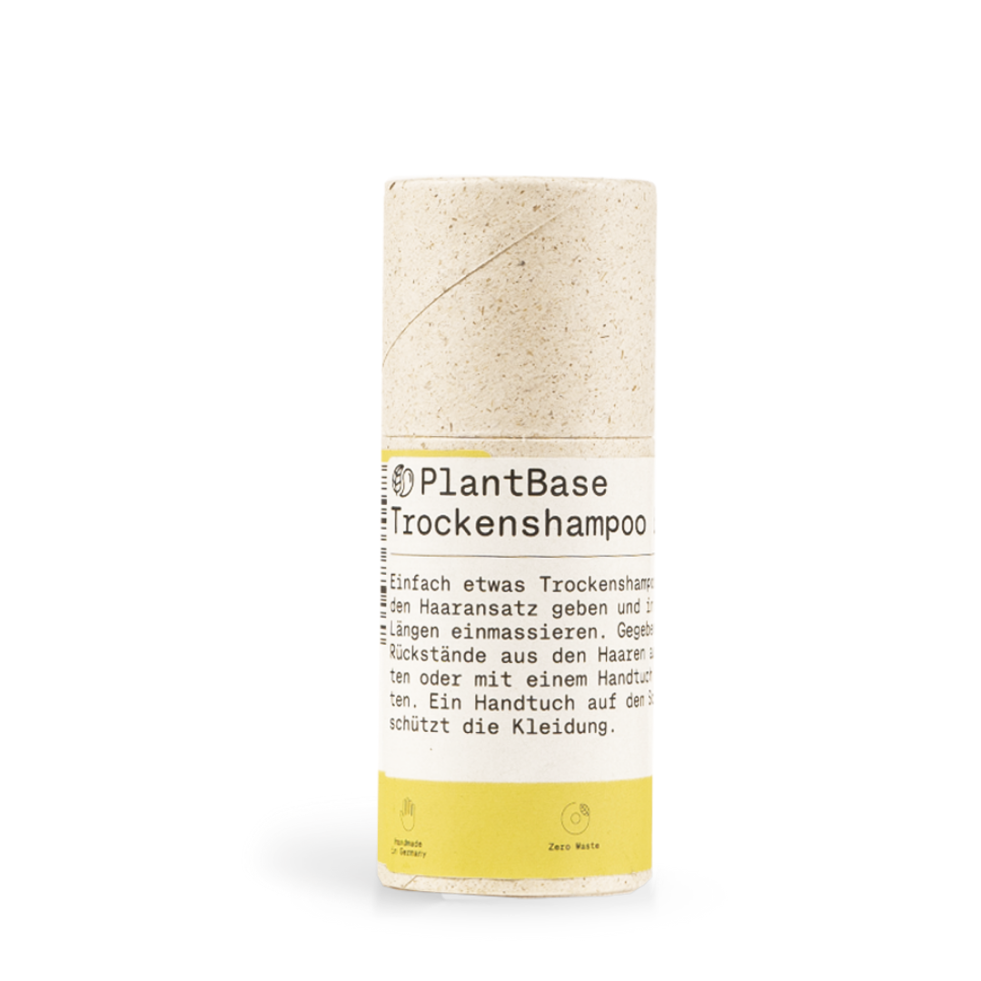 Zylindrische Verpackung des "PlantBase Trockenshampoo" mit Aufschrift und gelbem Etikett, auf weißem Hintergrund.