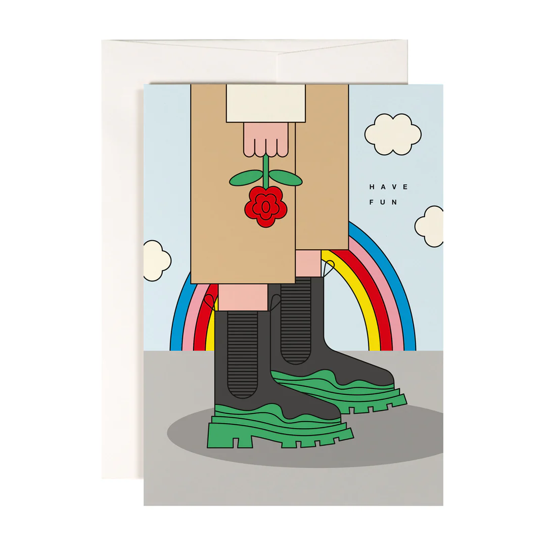 Illustrierte Karte, die Beine in hellbraunen Hosen und grünen Stiefeln zeigt, die eine rote Blume halten. Ein Regenbogen und Wolken sind im Hintergrund, mit HAVE FUN auf der rechten Seite geschrieben.