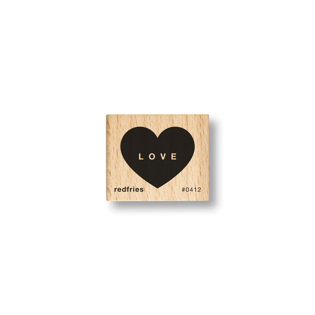 Ein Holzblockstempel mit einem schwarzen Herz in der Mitte und dem Wort LOVE im Inneren des Herzens. In der linken unteren Ecke steht redfries und in der rechten unteren Ecke steht #0412.