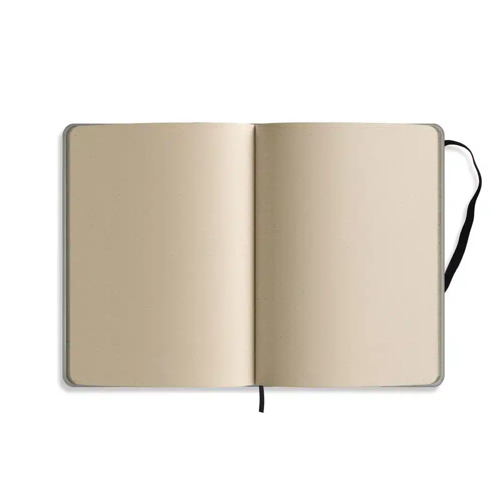 Ein aufgeschlagenes Notizbuch mit leeren beigen Seiten und einem Lesezeichen mit schwarzem Band, das flach auf einem weißen Hintergrund liegt.