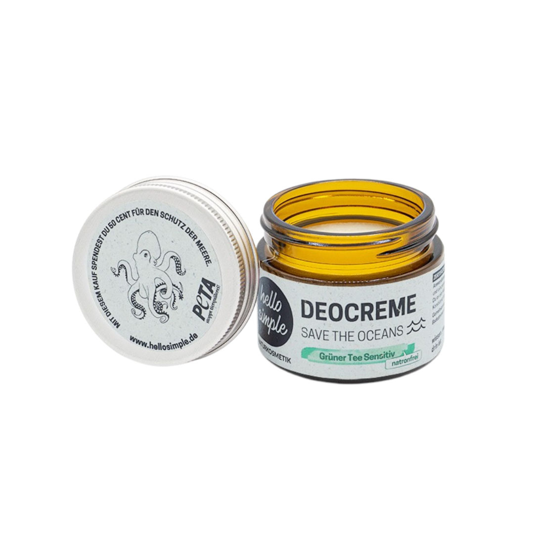 Ein offener, bernsteinfarbener Tiegel des Deodorants "Hello Simple Deocreme Save The Oceans" mit einem weißen Deckel, auf dem ein Oktopus abgebildet ist. Das Etikett weist auf "Grüner Tee Sensitiv" hin und hebt die natürlichen Inhaltsstoffe hervor.